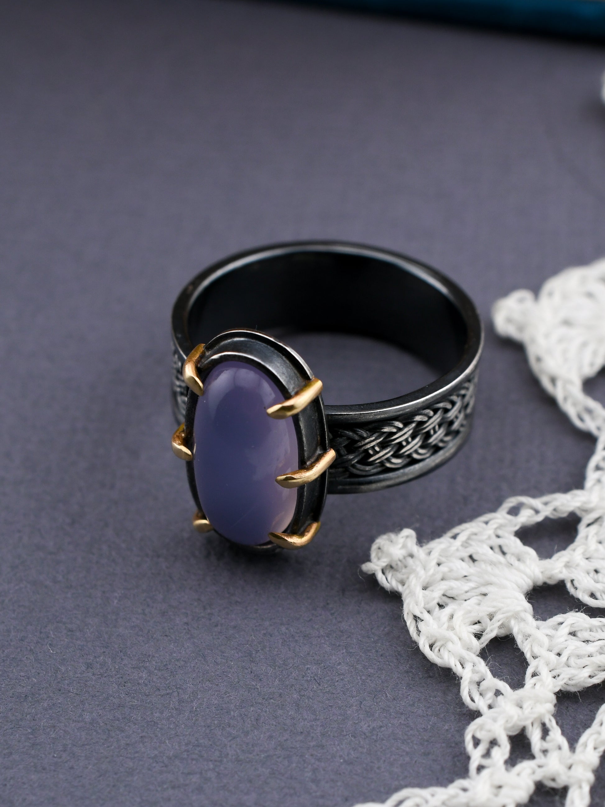 Black ring with a purple stone on a gray surface with white lace