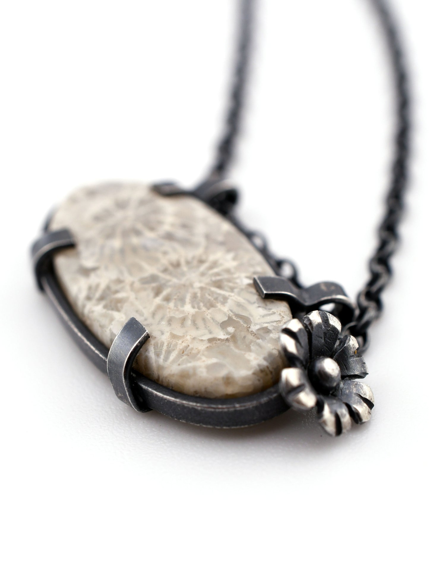 Necklace with a stone pendant and flower accents on a white background