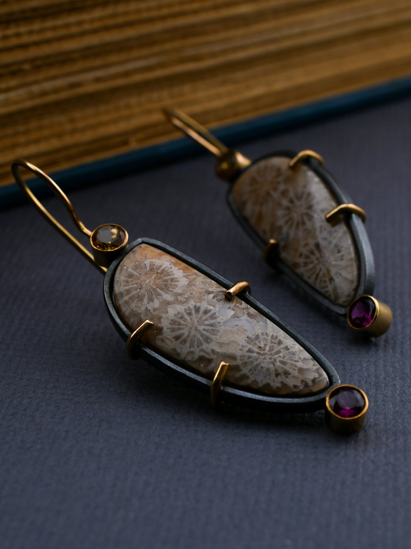 Pair of earrings with natural stone and gold accents on a dark surface