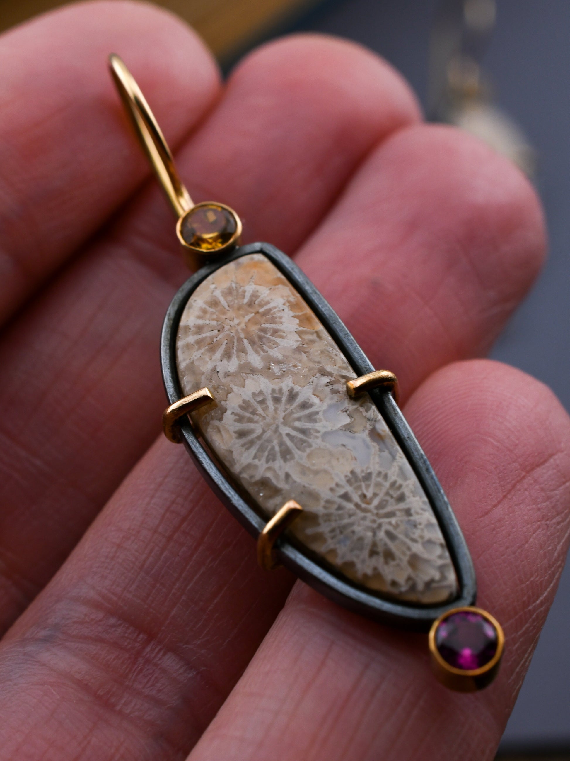 Jewelry with a stone and gold accents held in a hand