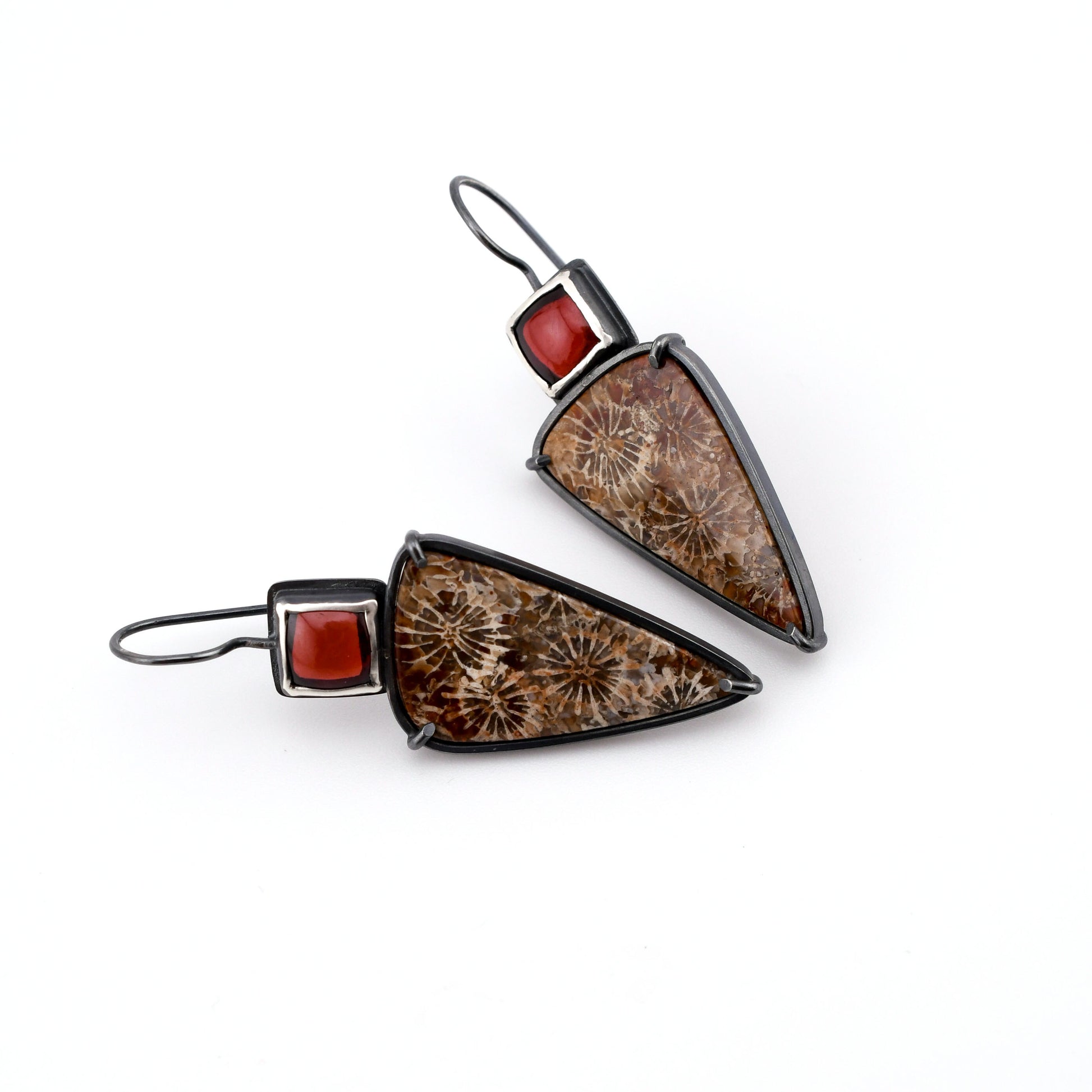Pair of earrings with brown triangular stones and red accents on a white background