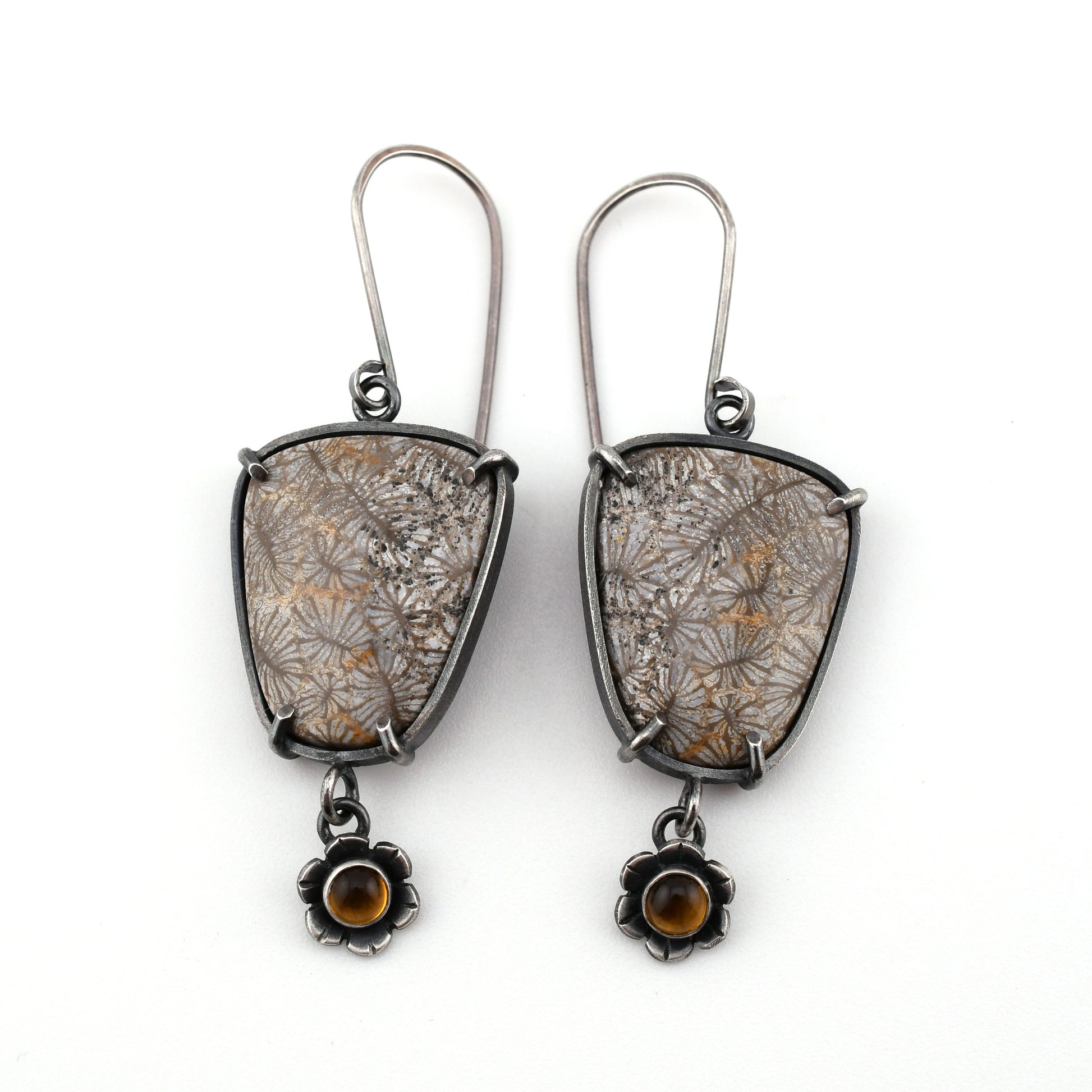 Pair of earrings with floral patterns and small stones on a white background