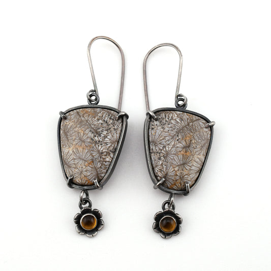 Pair of earrings with floral patterns and small stones on a white background