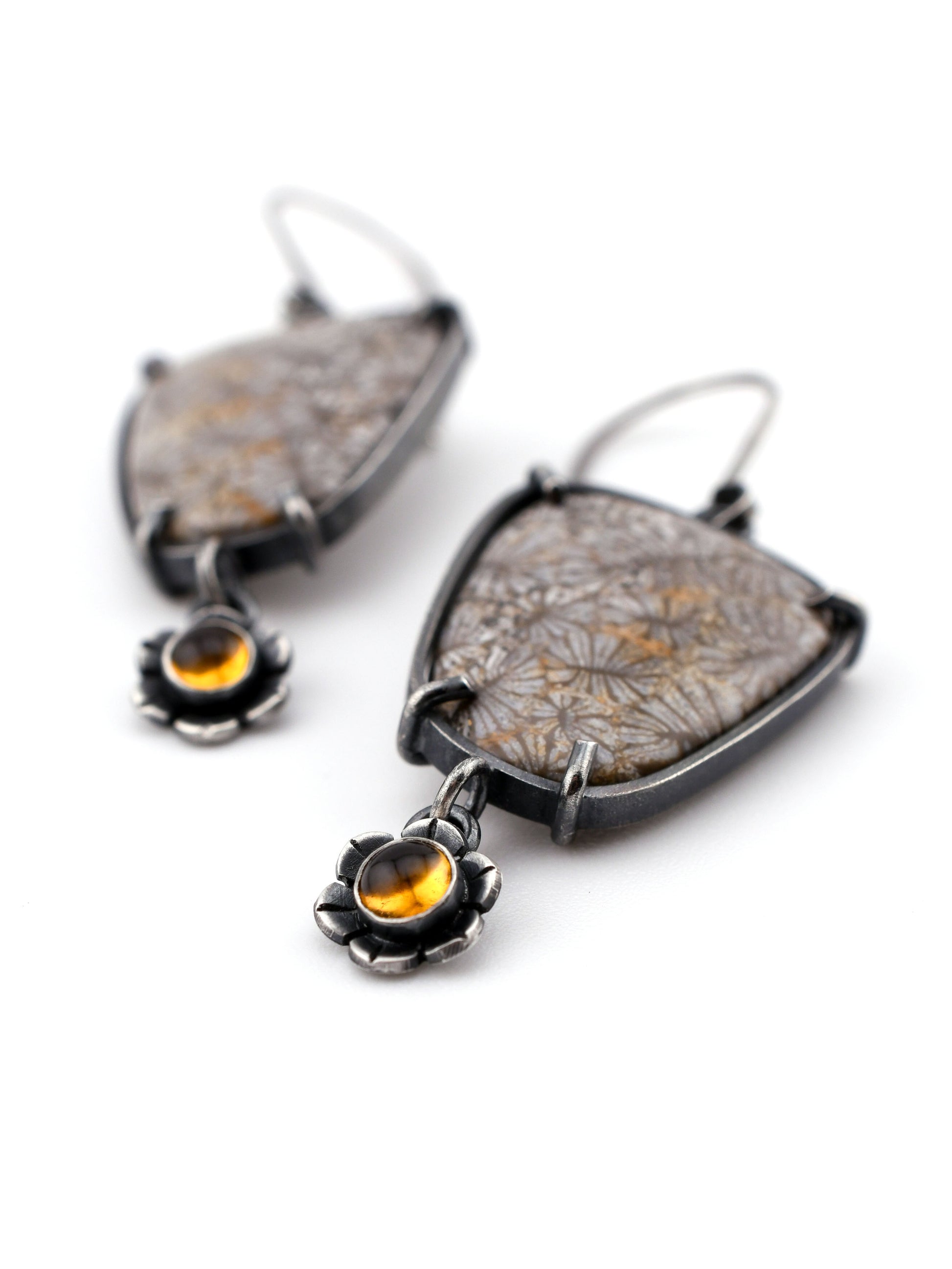 Pair of earrings with floral design and citrine stones on a white background