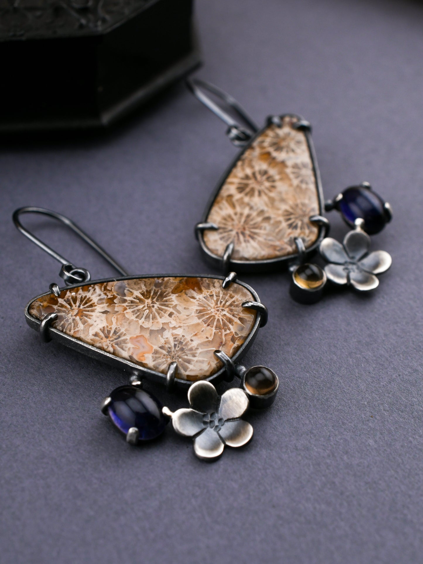 Pair of earrings with floral and gemstone details on a dark surface