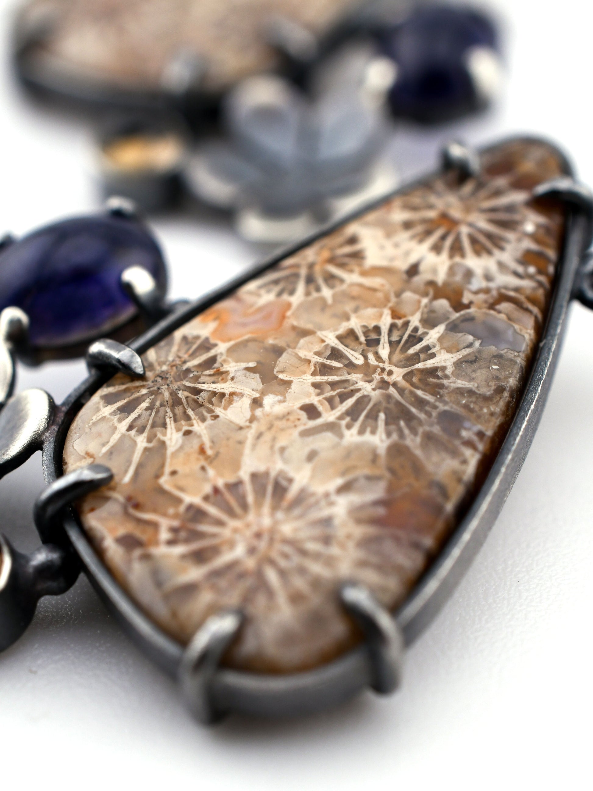 Close-up of an earring with a fossil coral on a white background