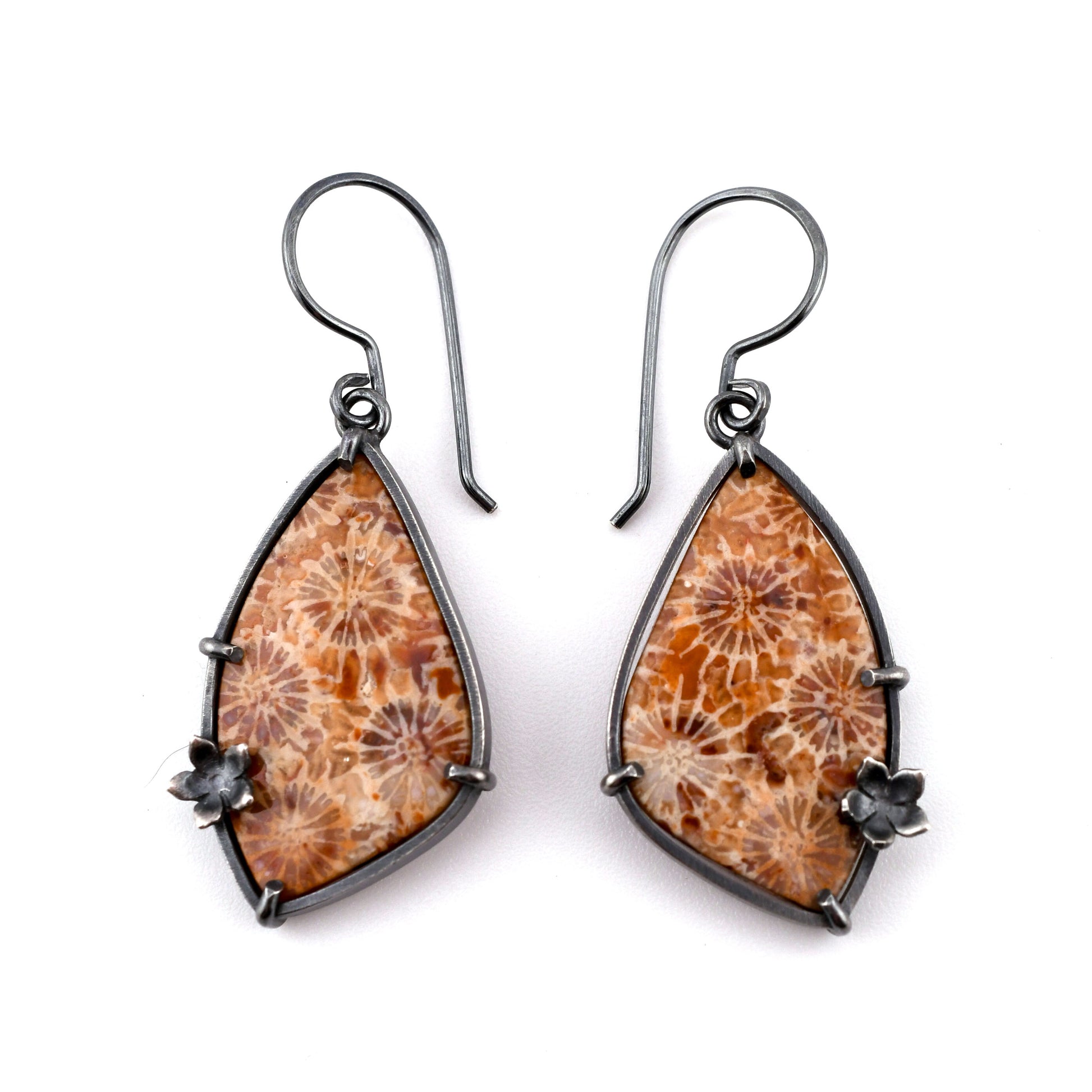 Wing-shaped earrings with orange fossil corals and black accents on a white background
