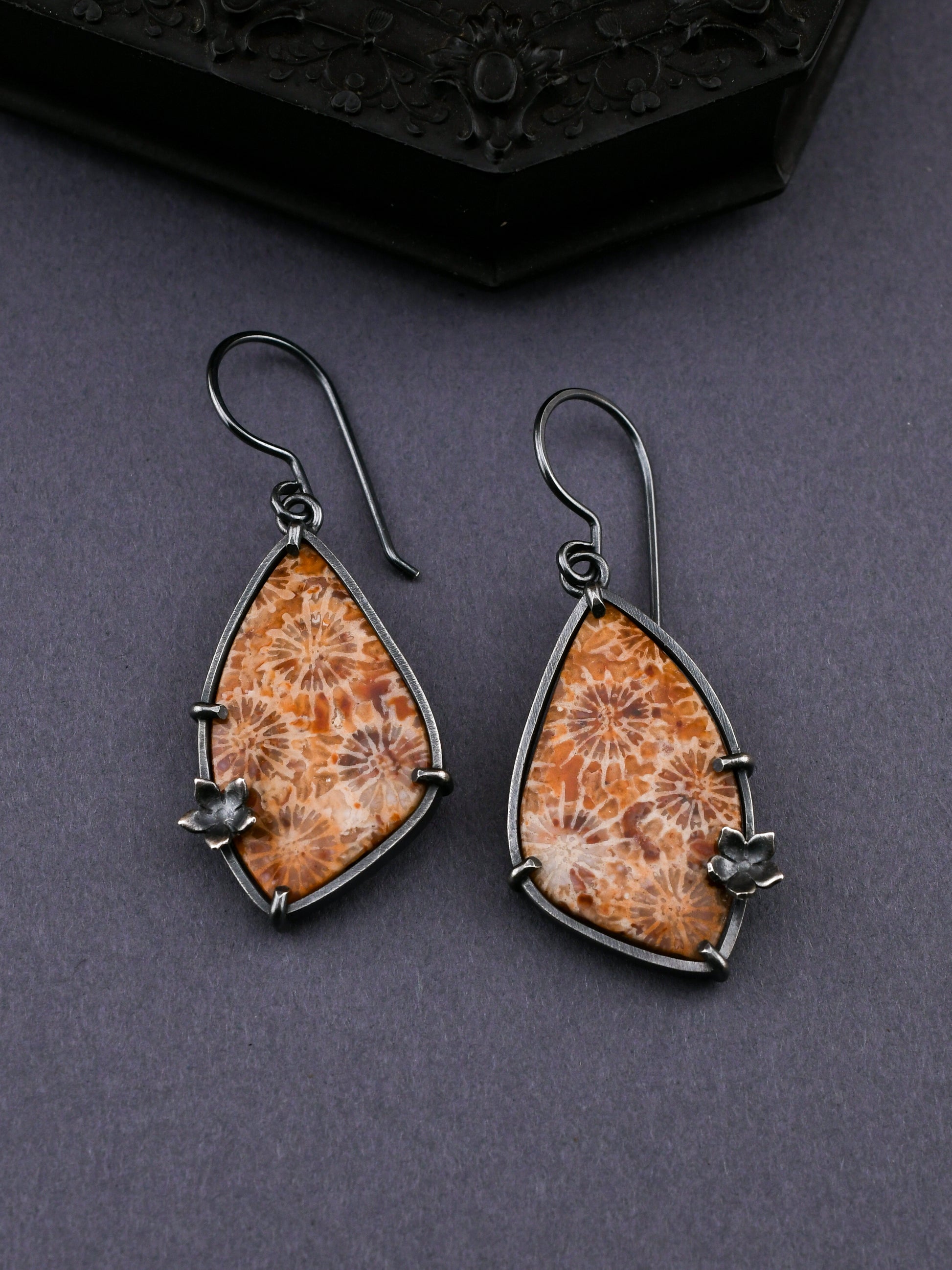 Wing-shaped earrings with fossilized corals on a dark background
