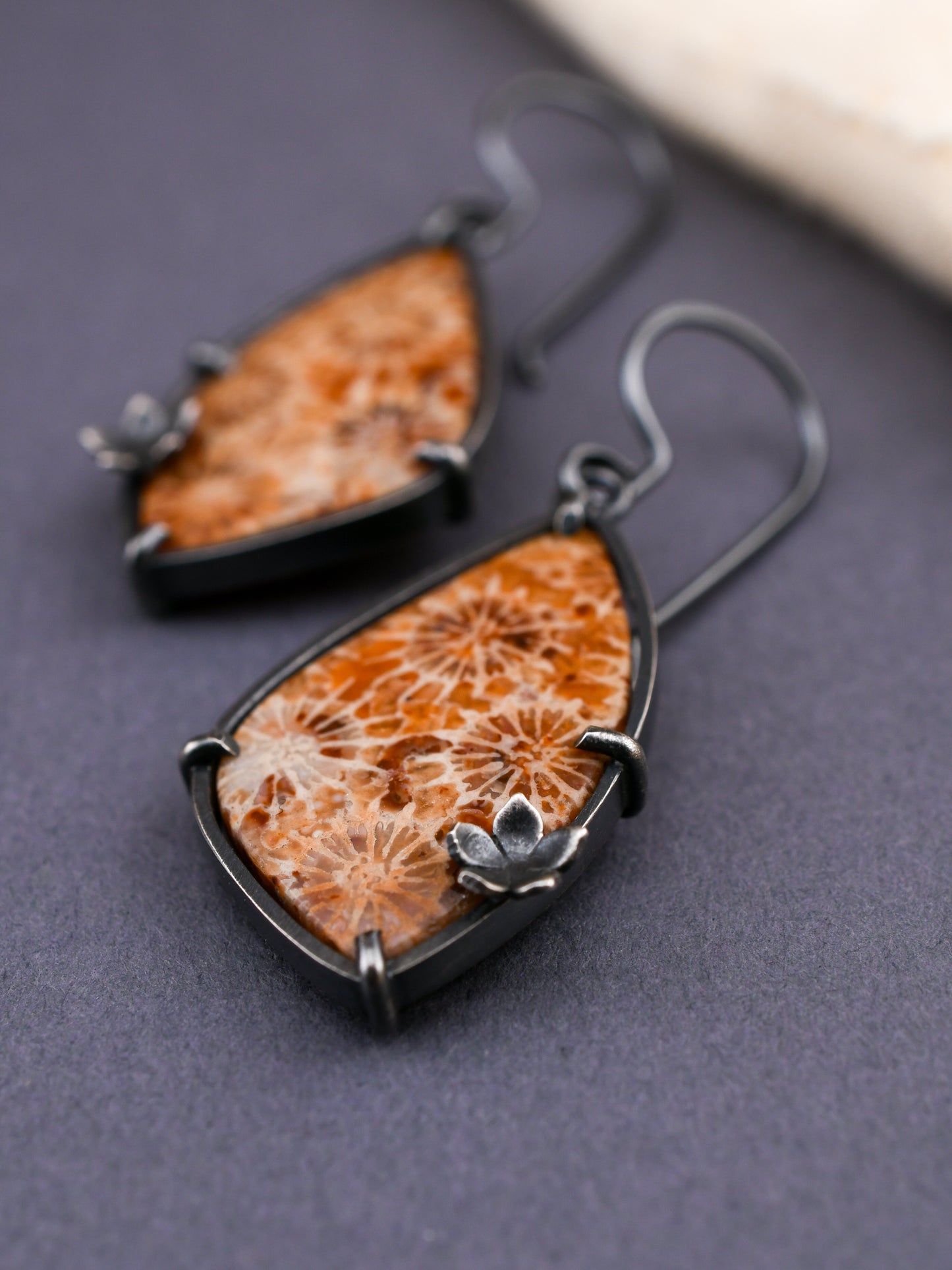 Pair of earrings with orange and white floral design on a gray background