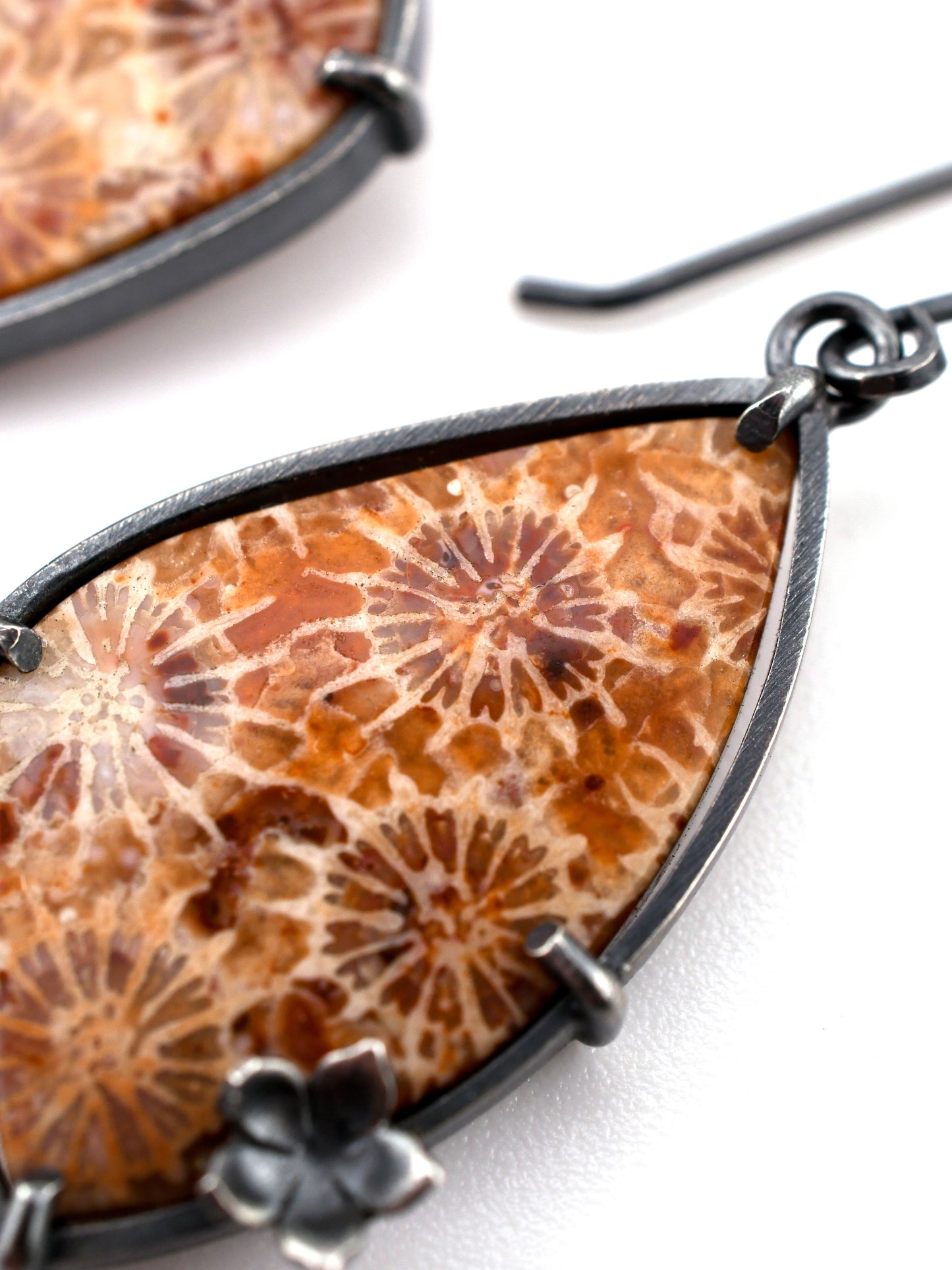 Earring with orange floral pattern and black metal frame on a white background