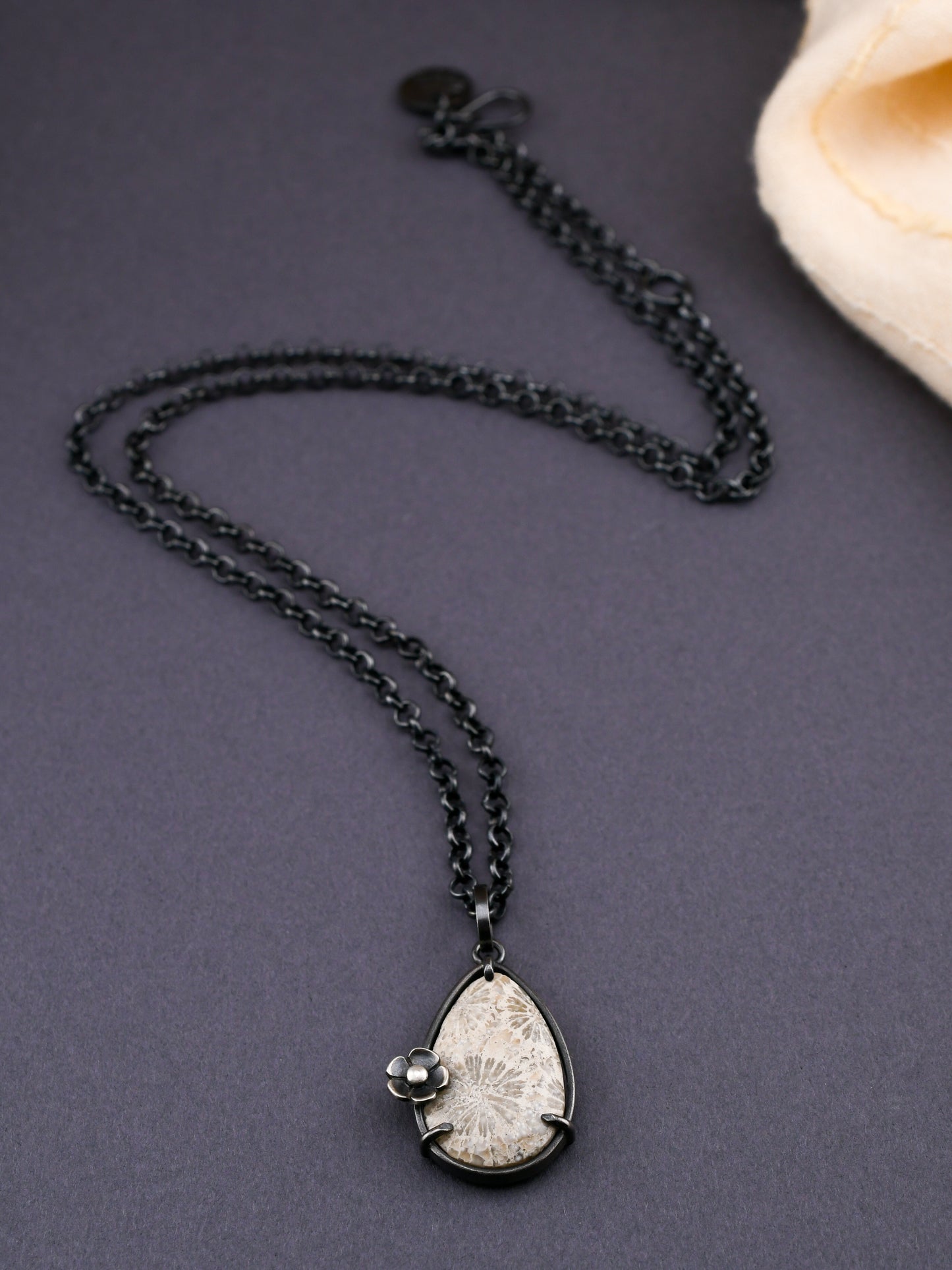Necklace with a teardrop-shaped pendant on a dark surface