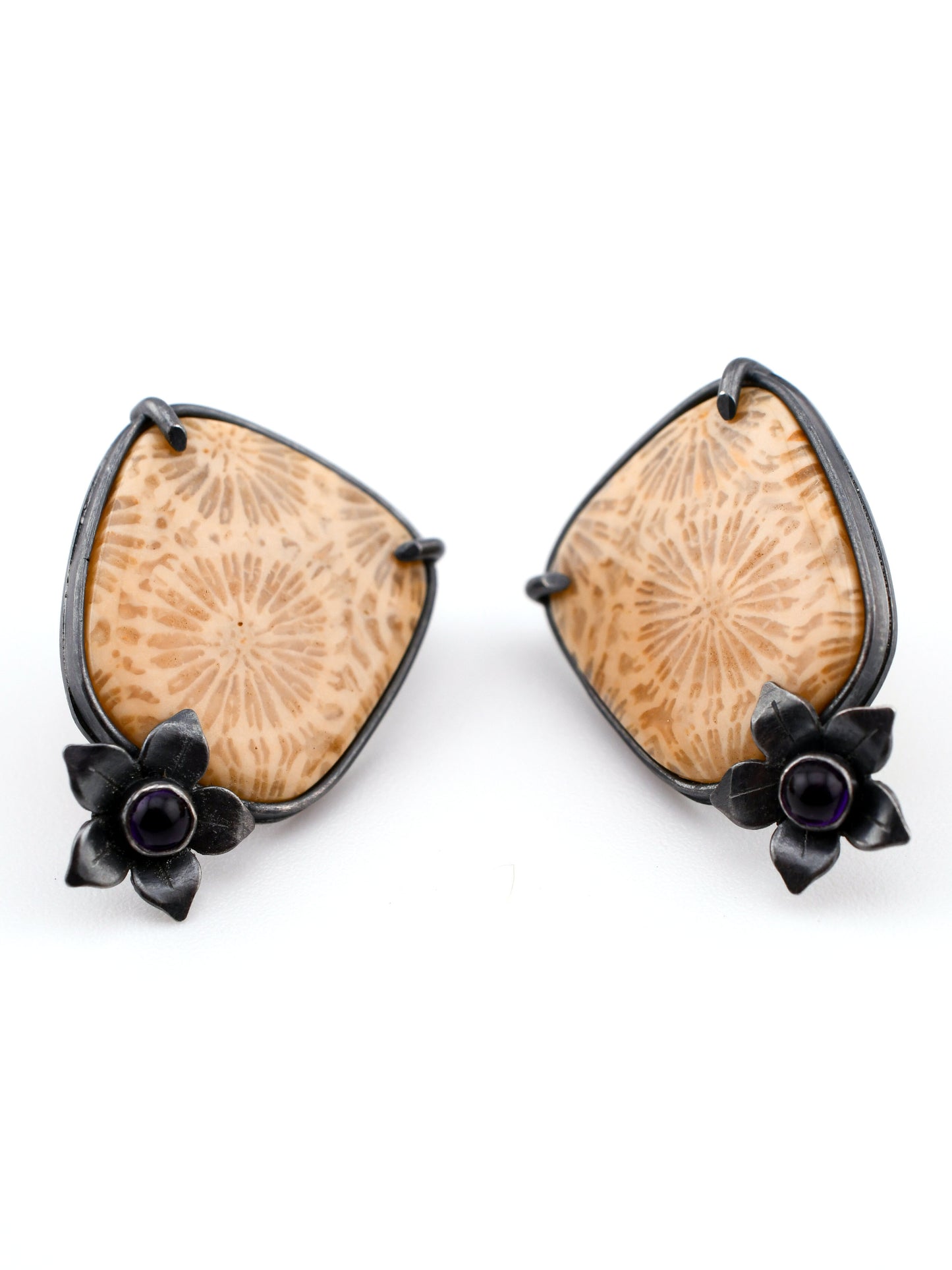 Pair of earrings with fossilized corals and black floral accents on a white background