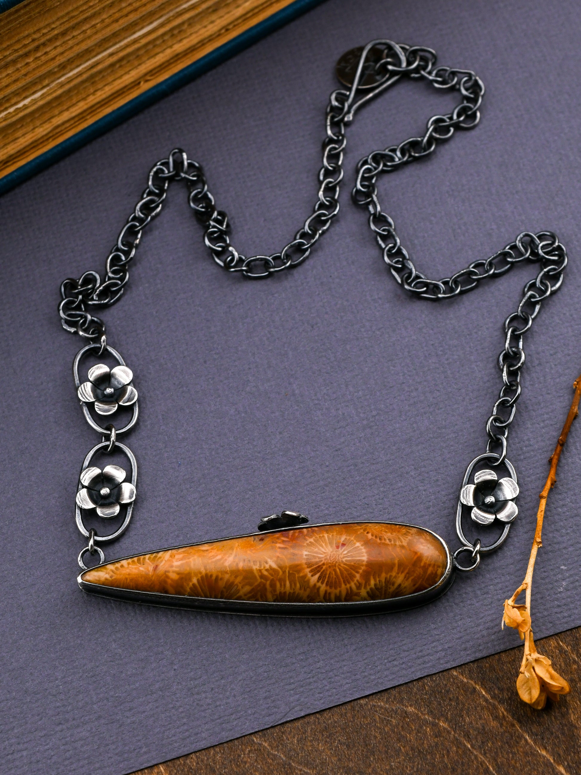 Necklace with a dark golden-colored pendant on a dark surface