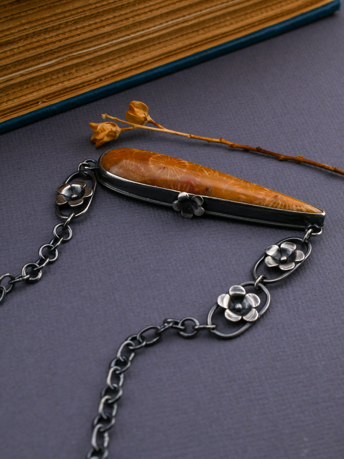 Silver chain with a decorative pendant on a dark surface