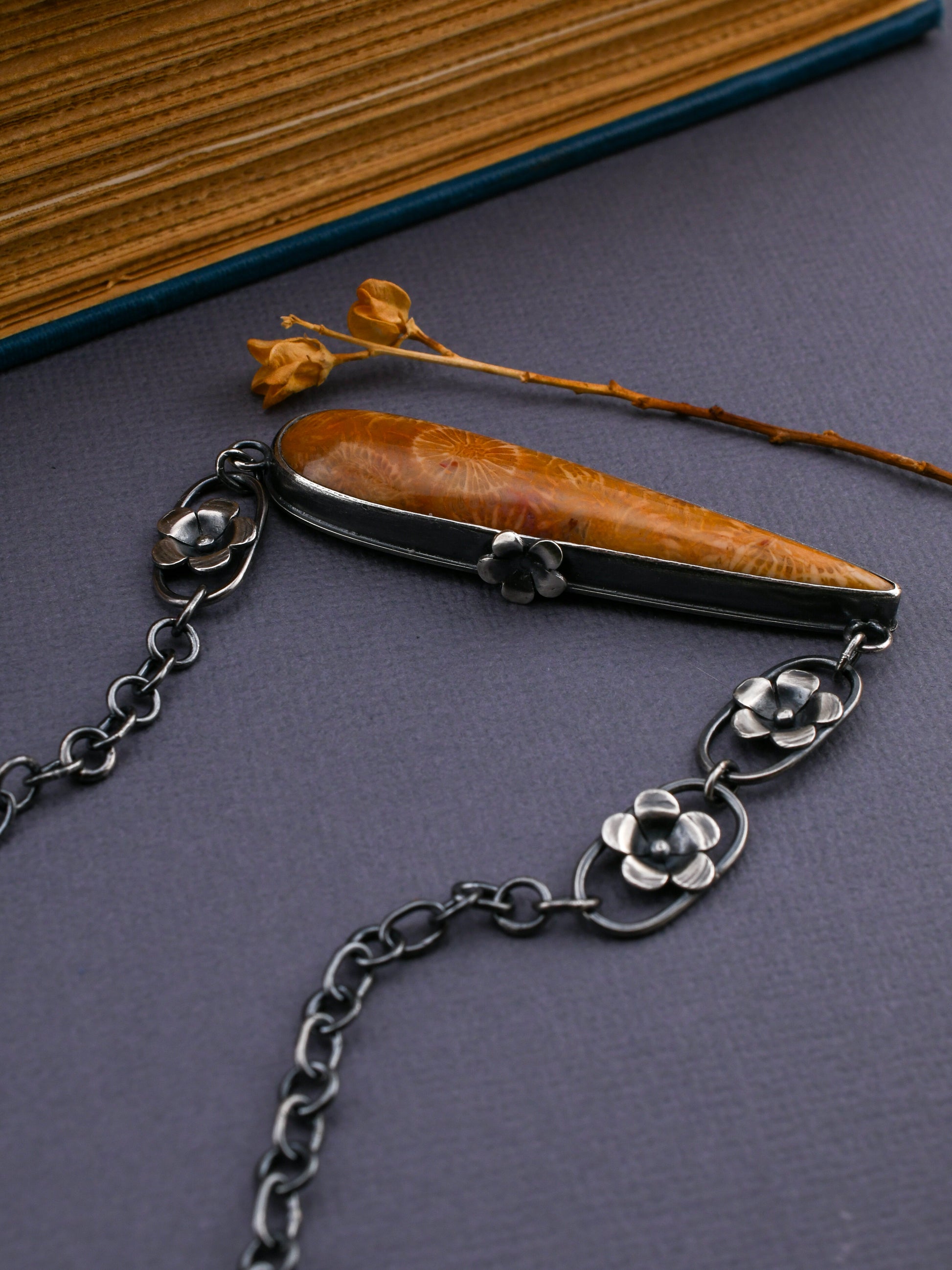 Silver chain with a decorative pendant on a dark surface