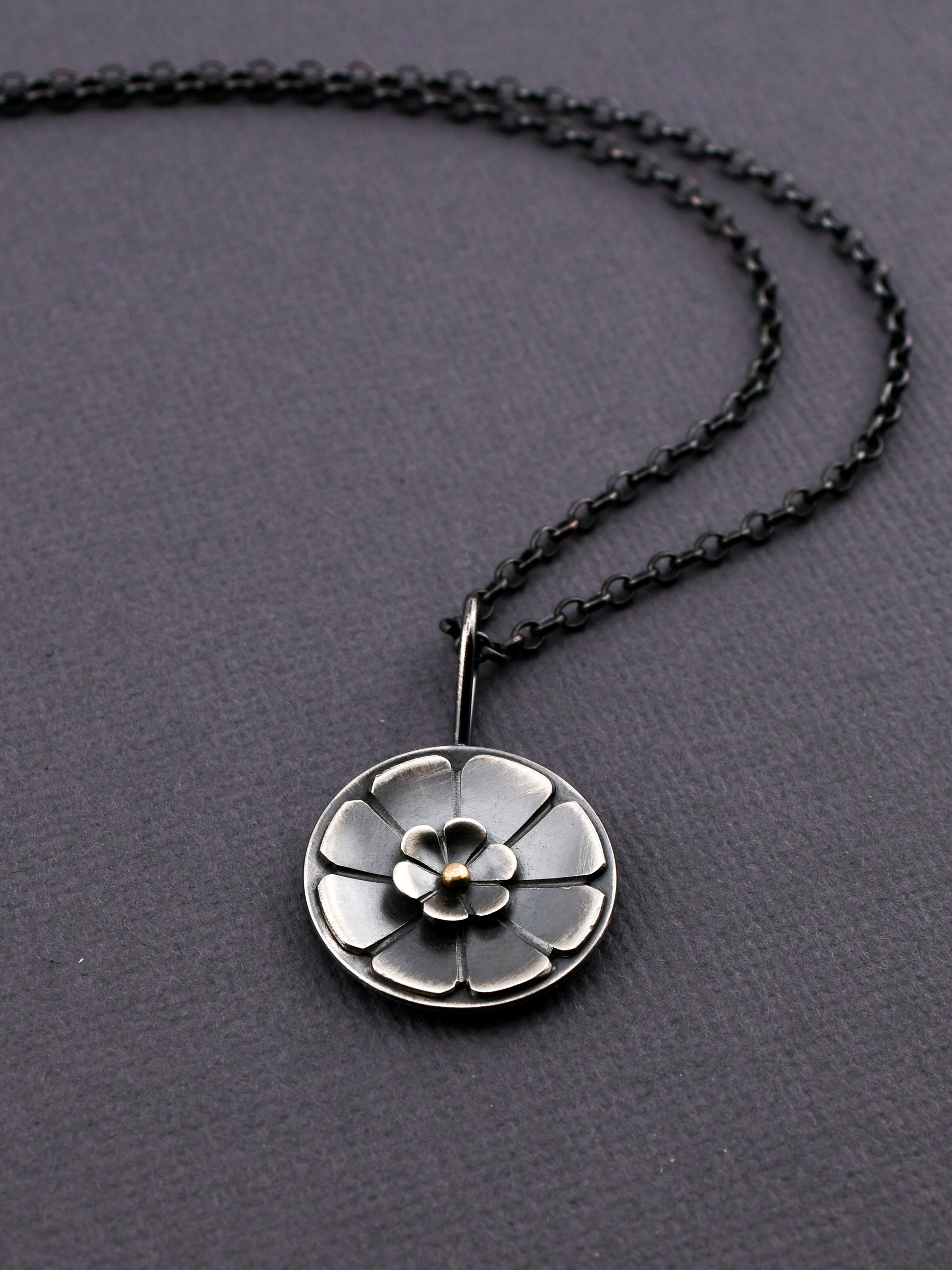 Necklace with a silver floral pendant on a dark gray background