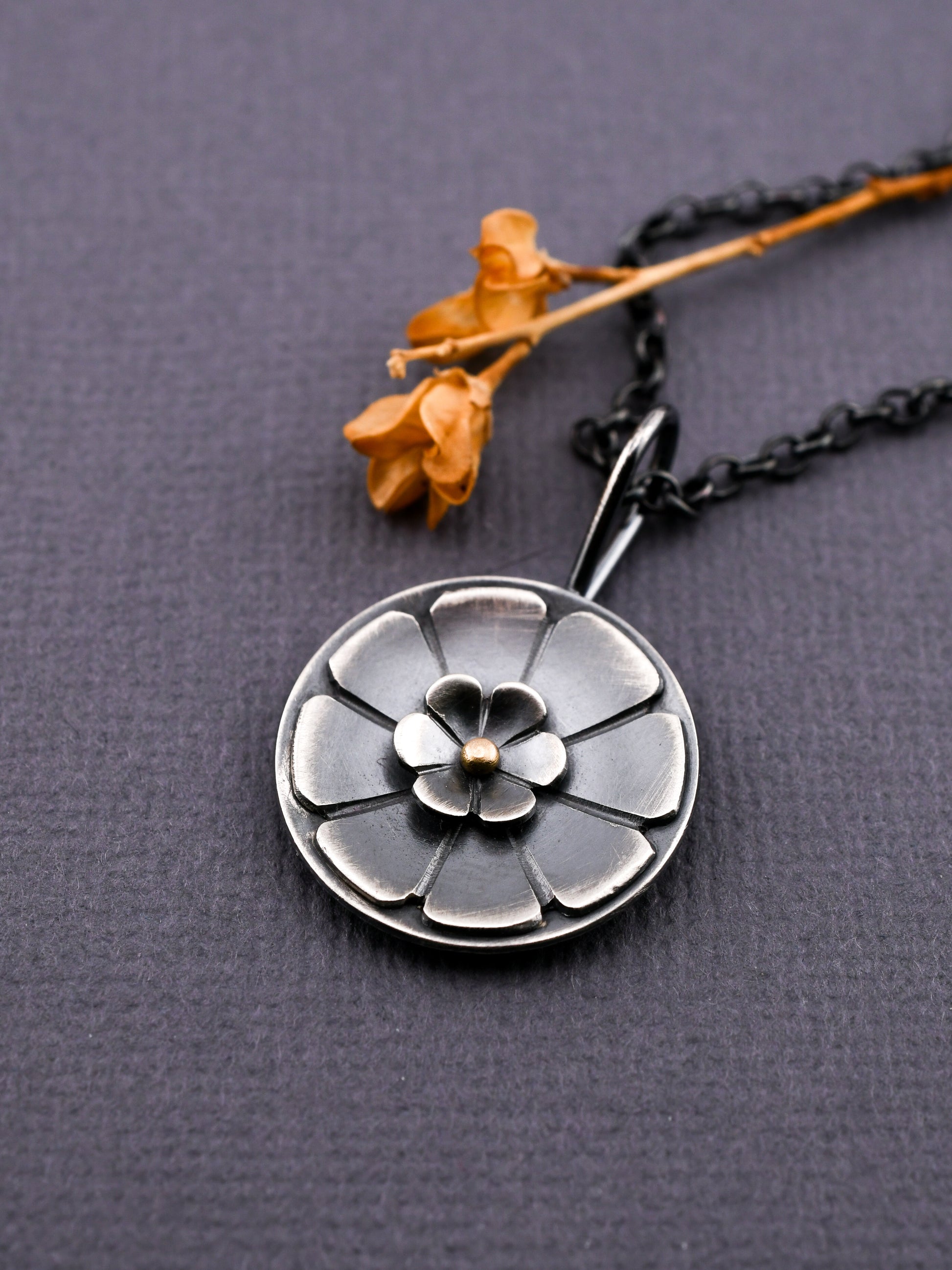 Silver floral pendant necklace on a dark gray background
