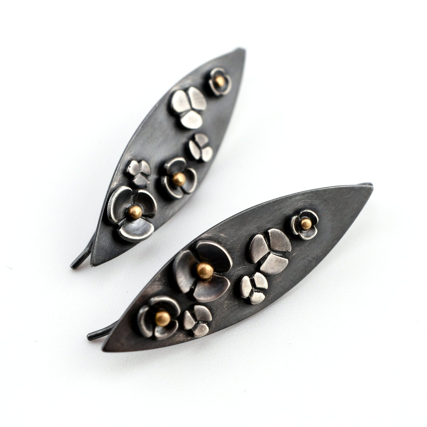 Pair of leaf-shaped earrings with floral designs on a white background