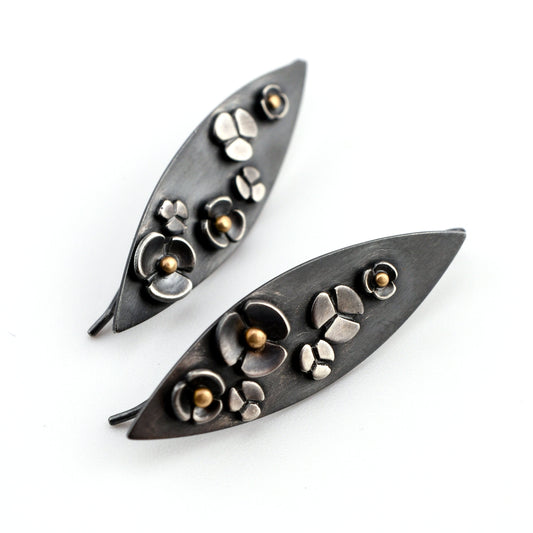 Pair of leaf-shaped earrings with floral designs on a white background