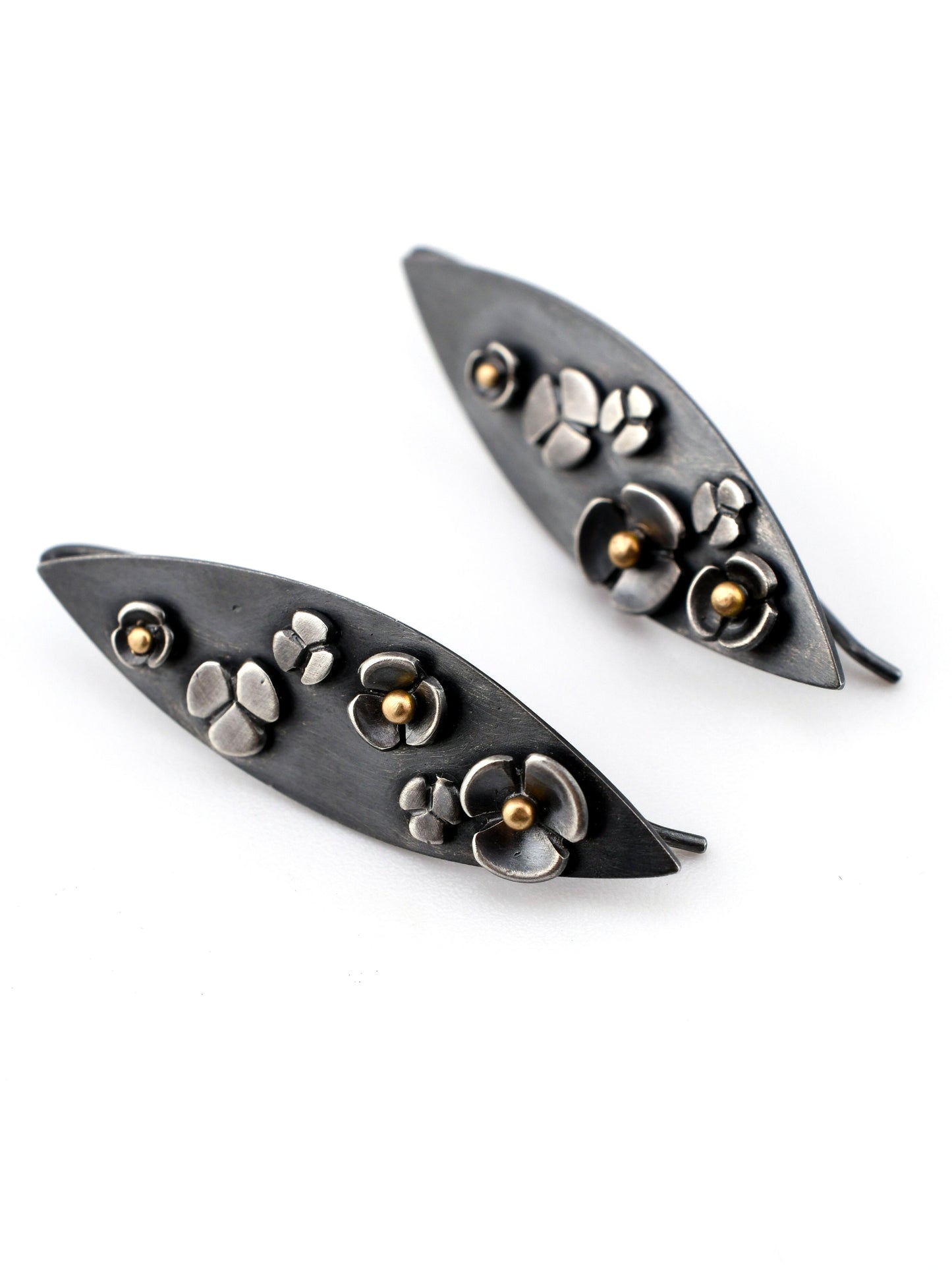 Pair of leaf-shaped earrings with floral designs on a white background