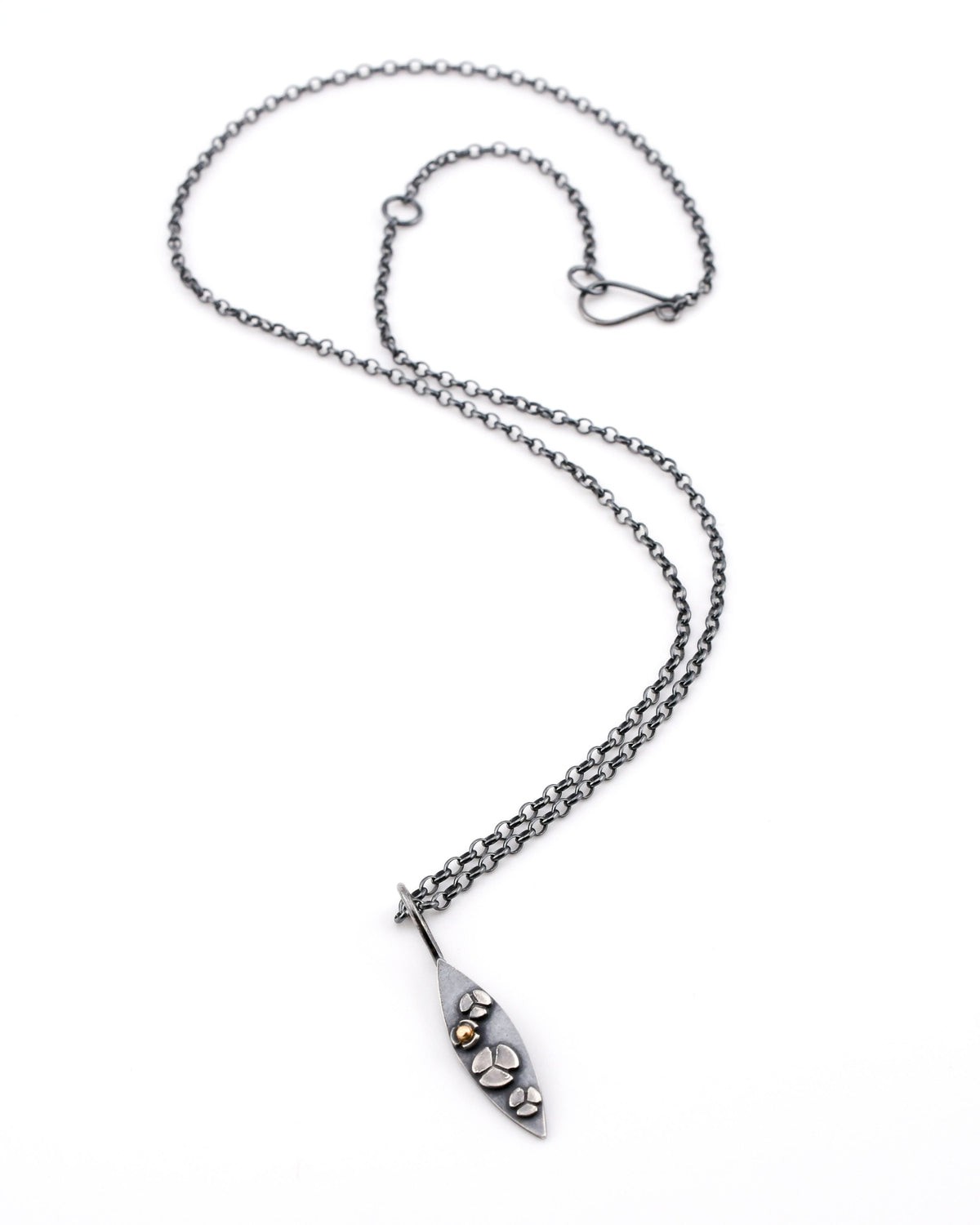 Blackened silver necklace with marquis-shaped pendant featuring delicate flowers, one with a 14k gold center, on a white background