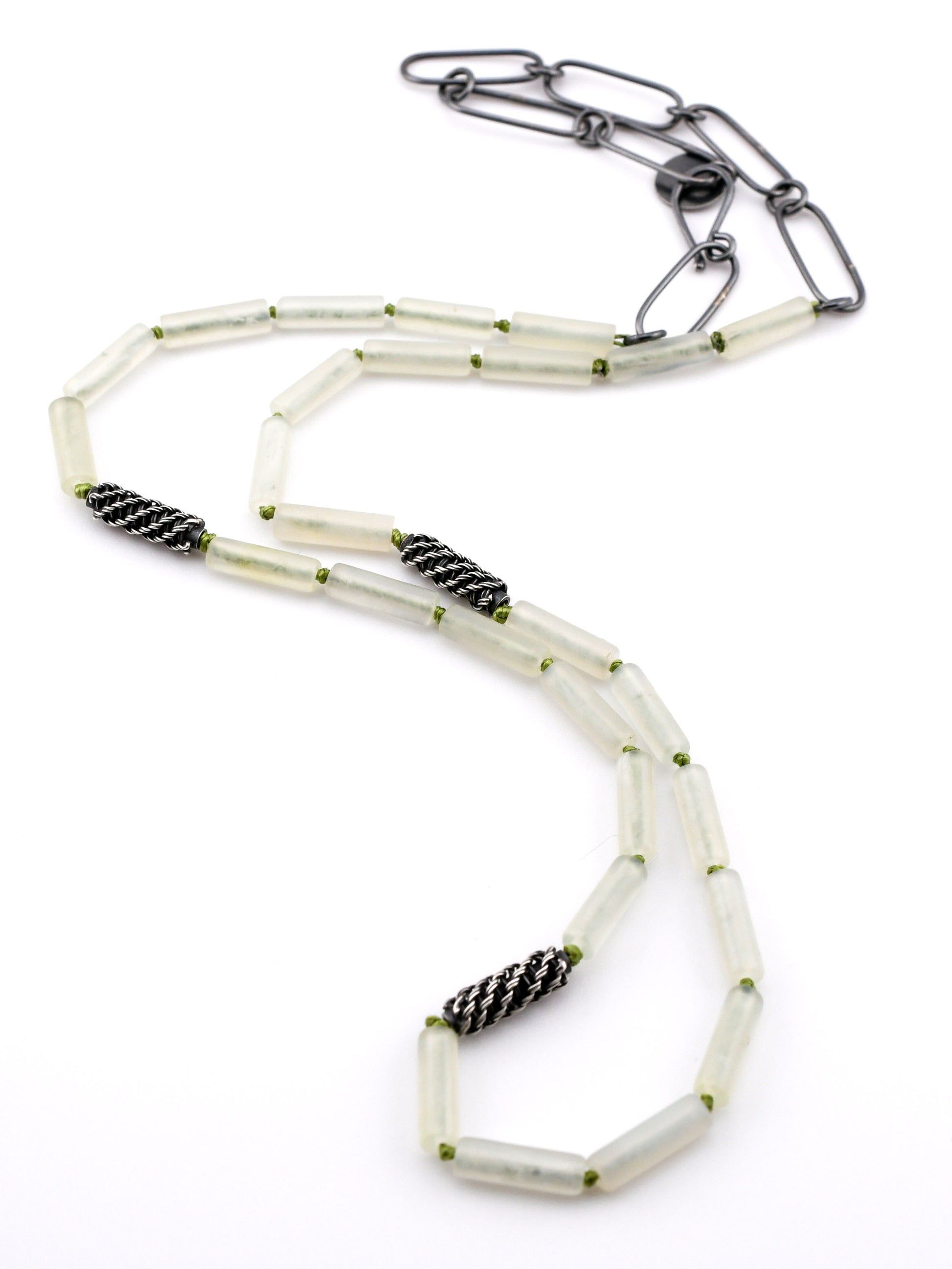 Necklace with pale green beads and black silver accents on a white background