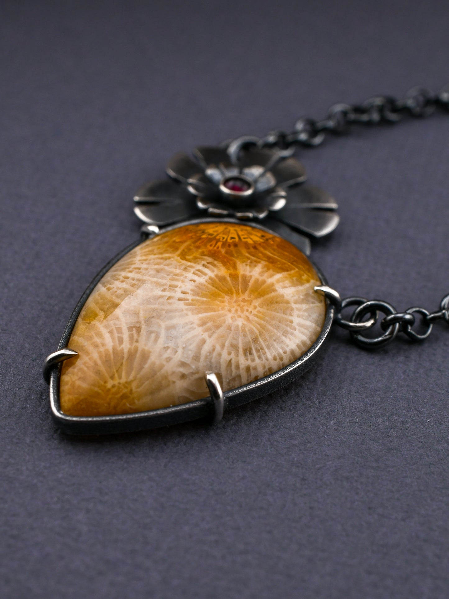 Necklace with a large amber-colored stone and silver chain on a dark background