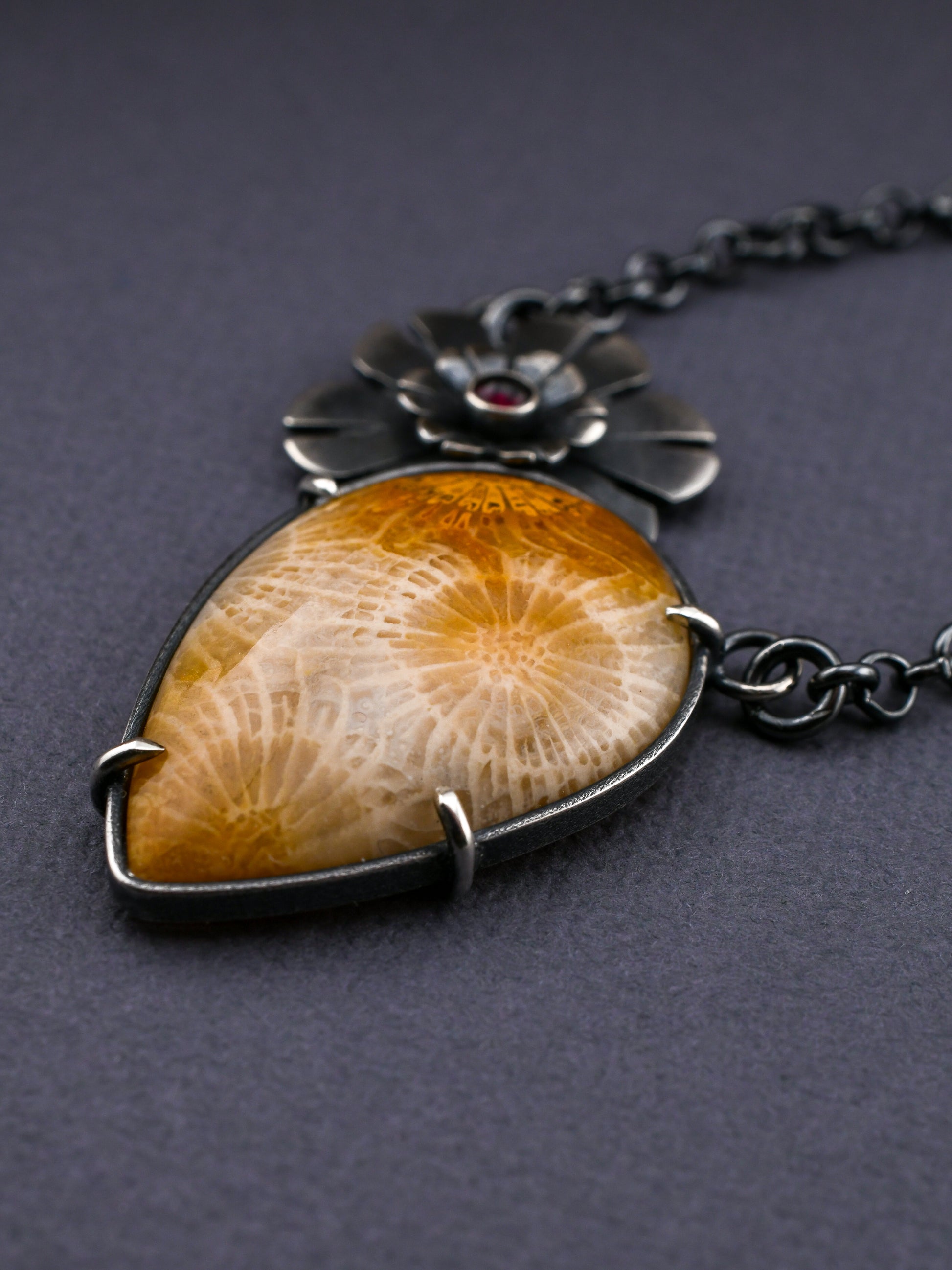 Necklace with a large amber-colored stone and silver chain on a dark background