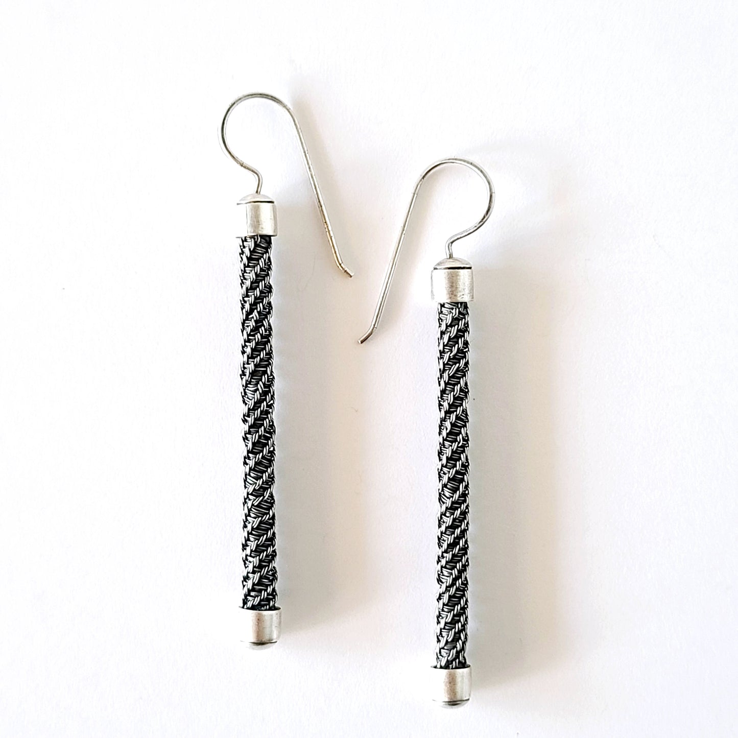 Pair of earrings with braided design on a white background