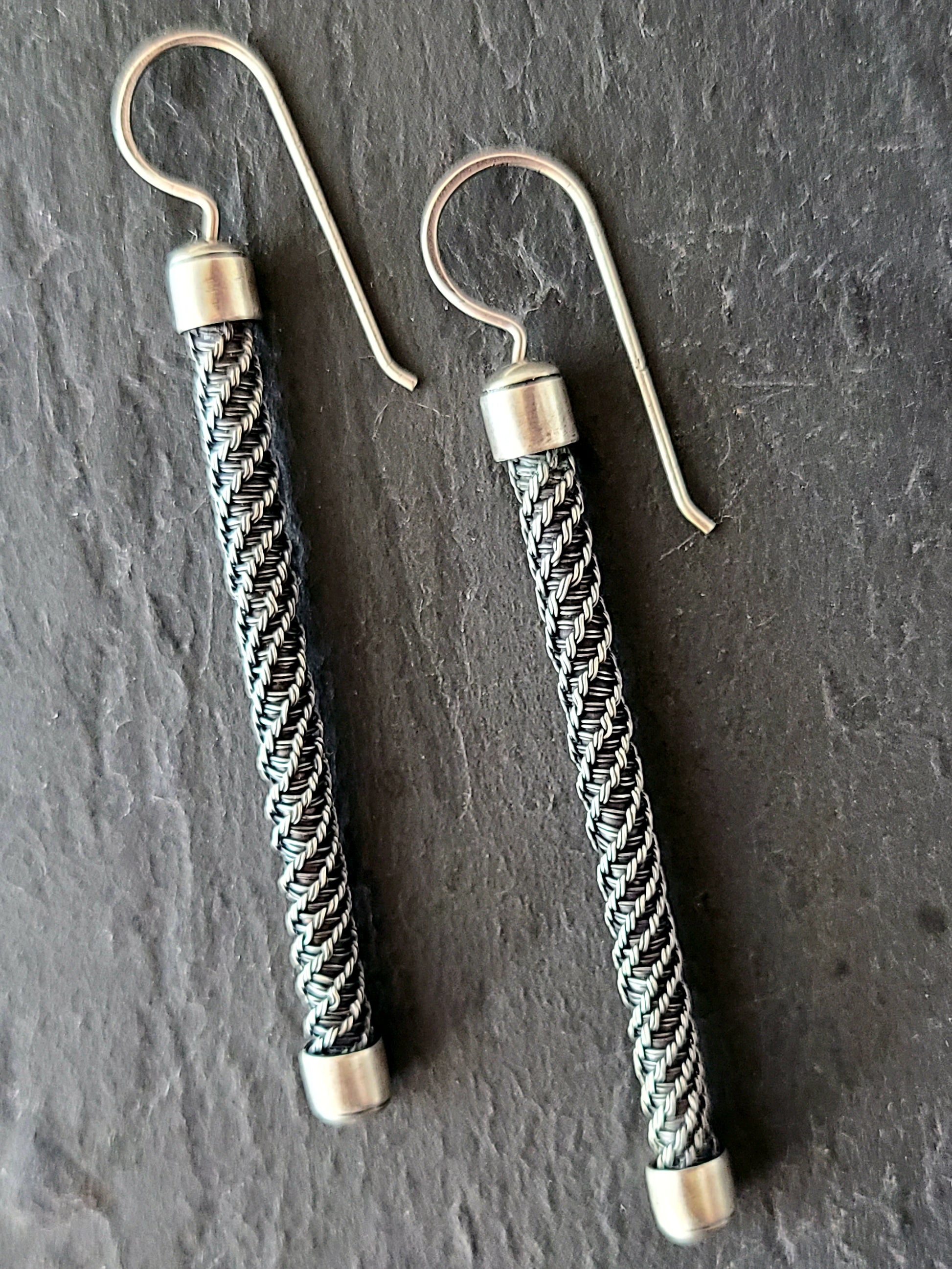 Long earrings with twisted and braided wire design on a black background