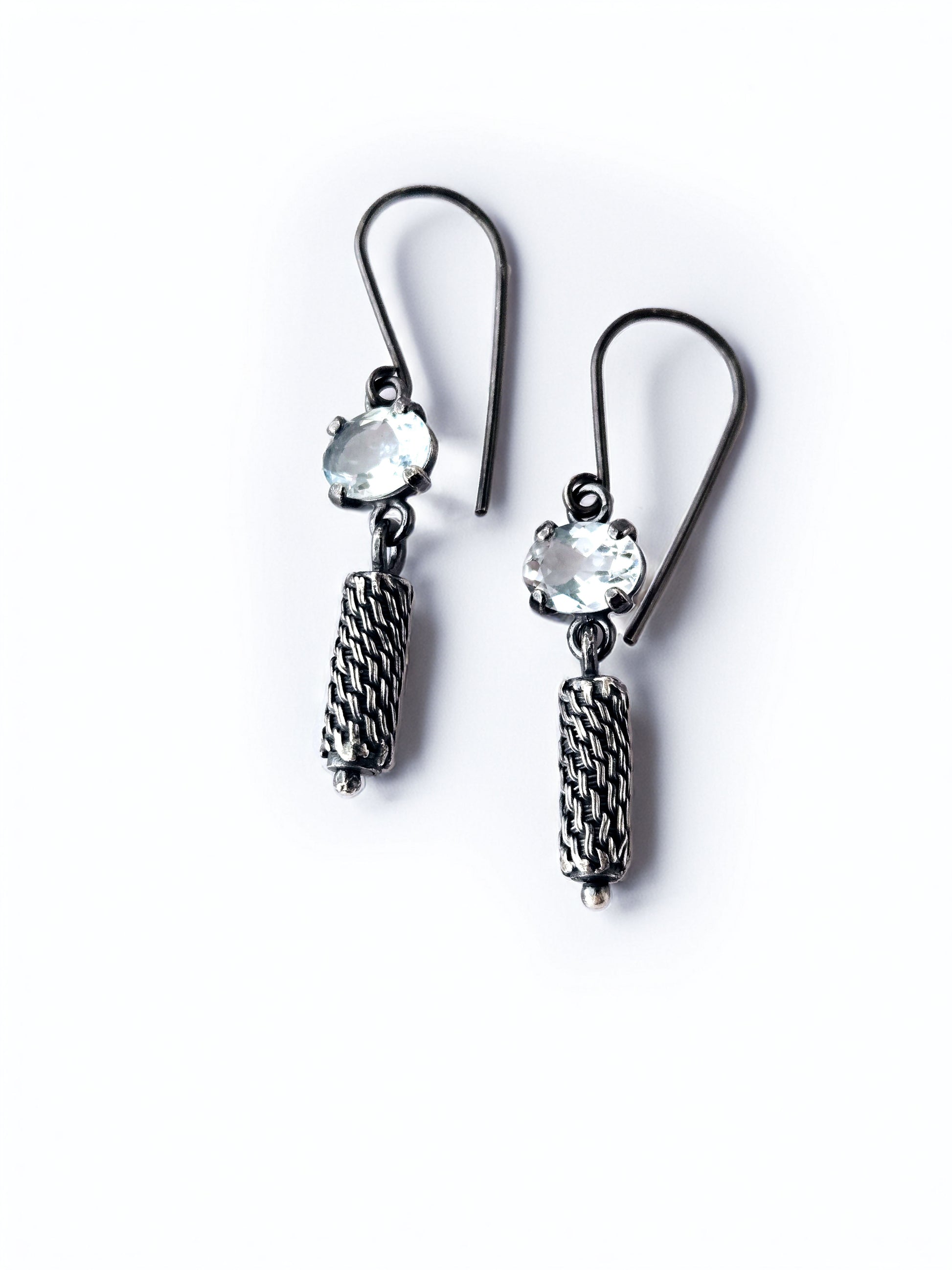 Pair of silver earrings with ice blue gemstones on a white background