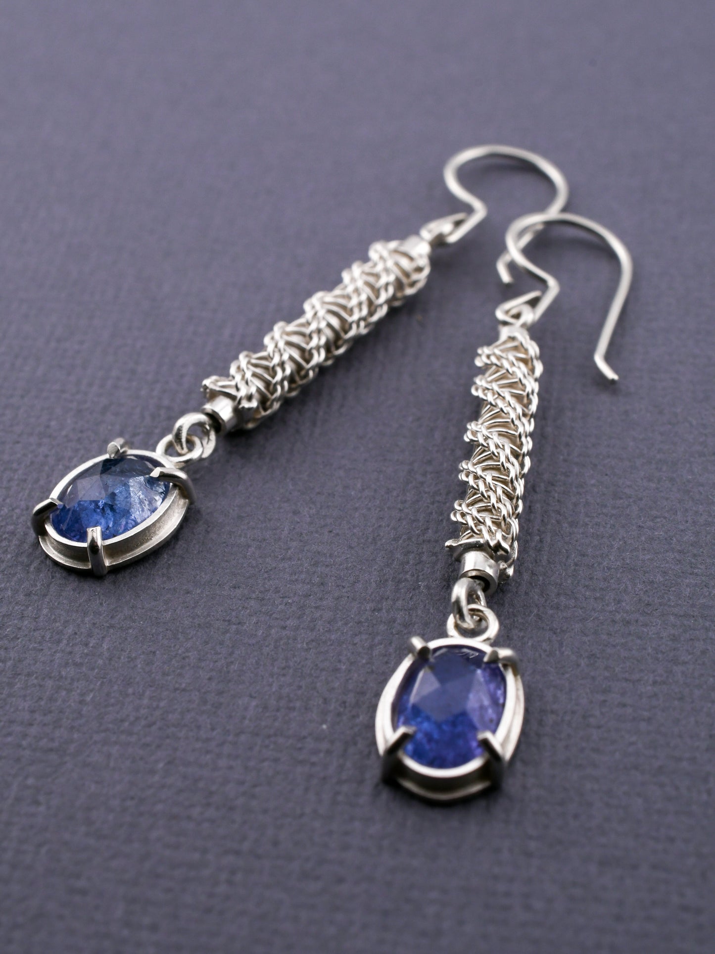 Silver earrings with blue gemstones on a dark background