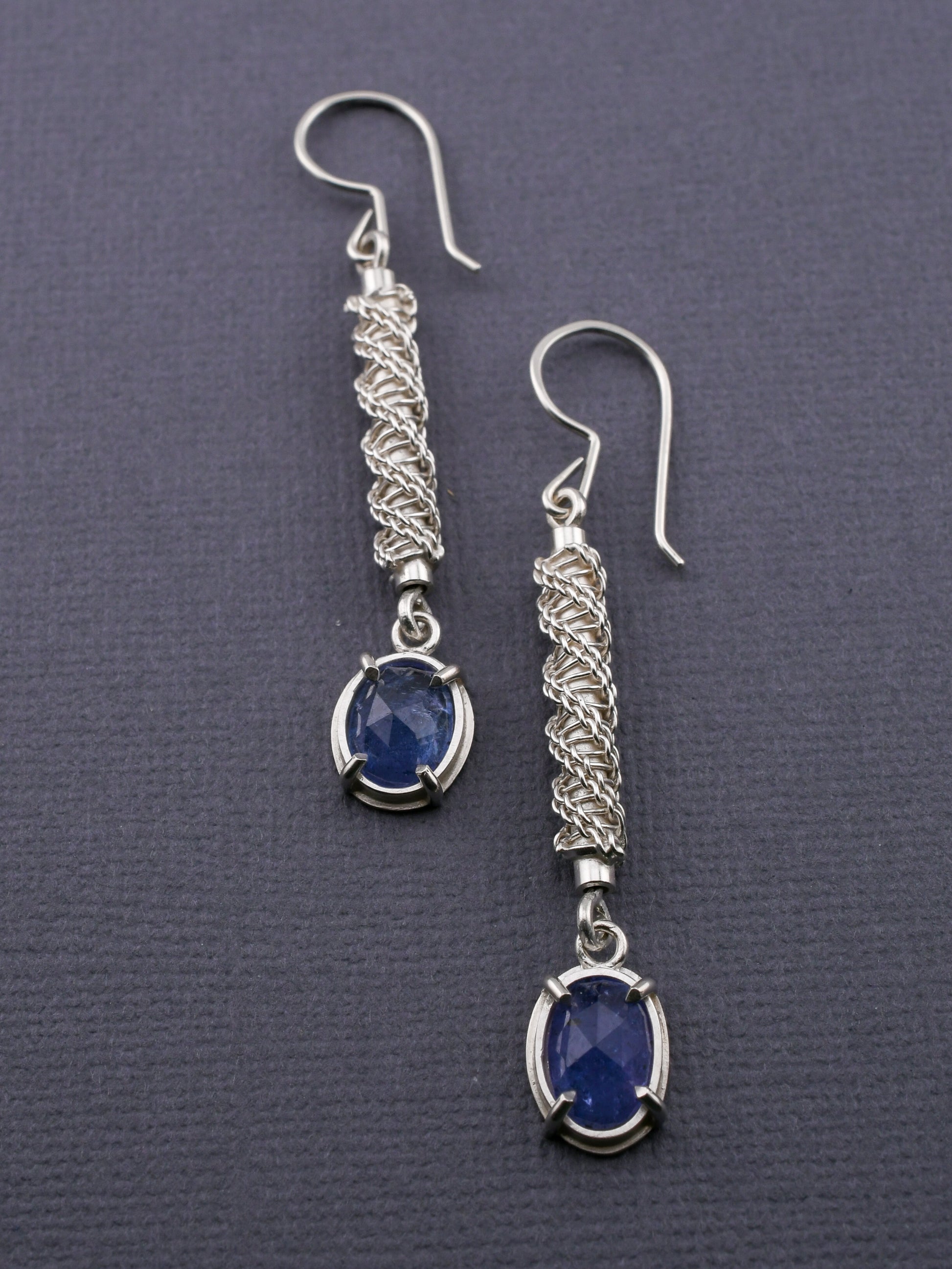 Silver earrings with blue gemstones on a gray background