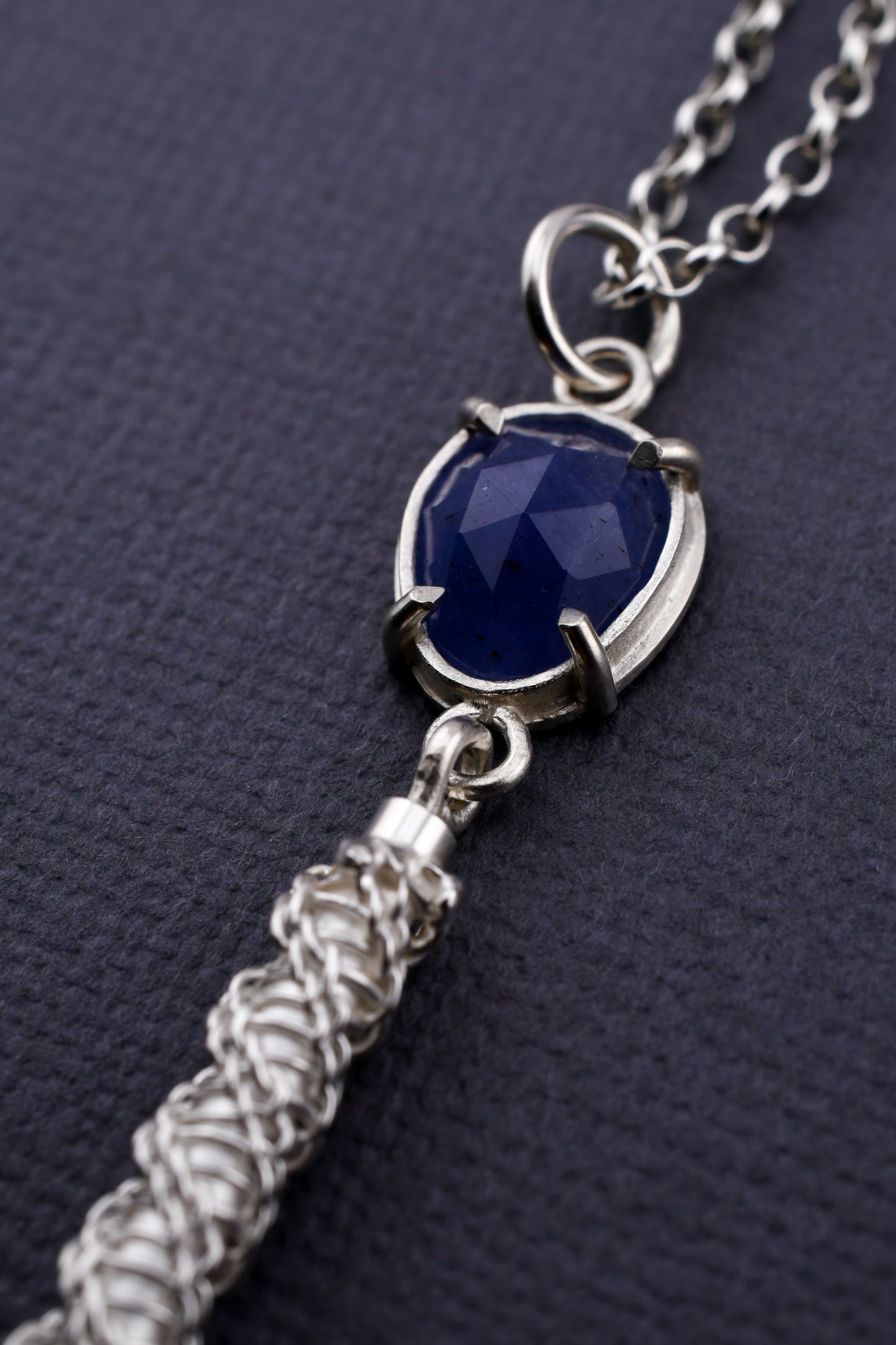 Necklace with blue pendant and silver chain on a dark background