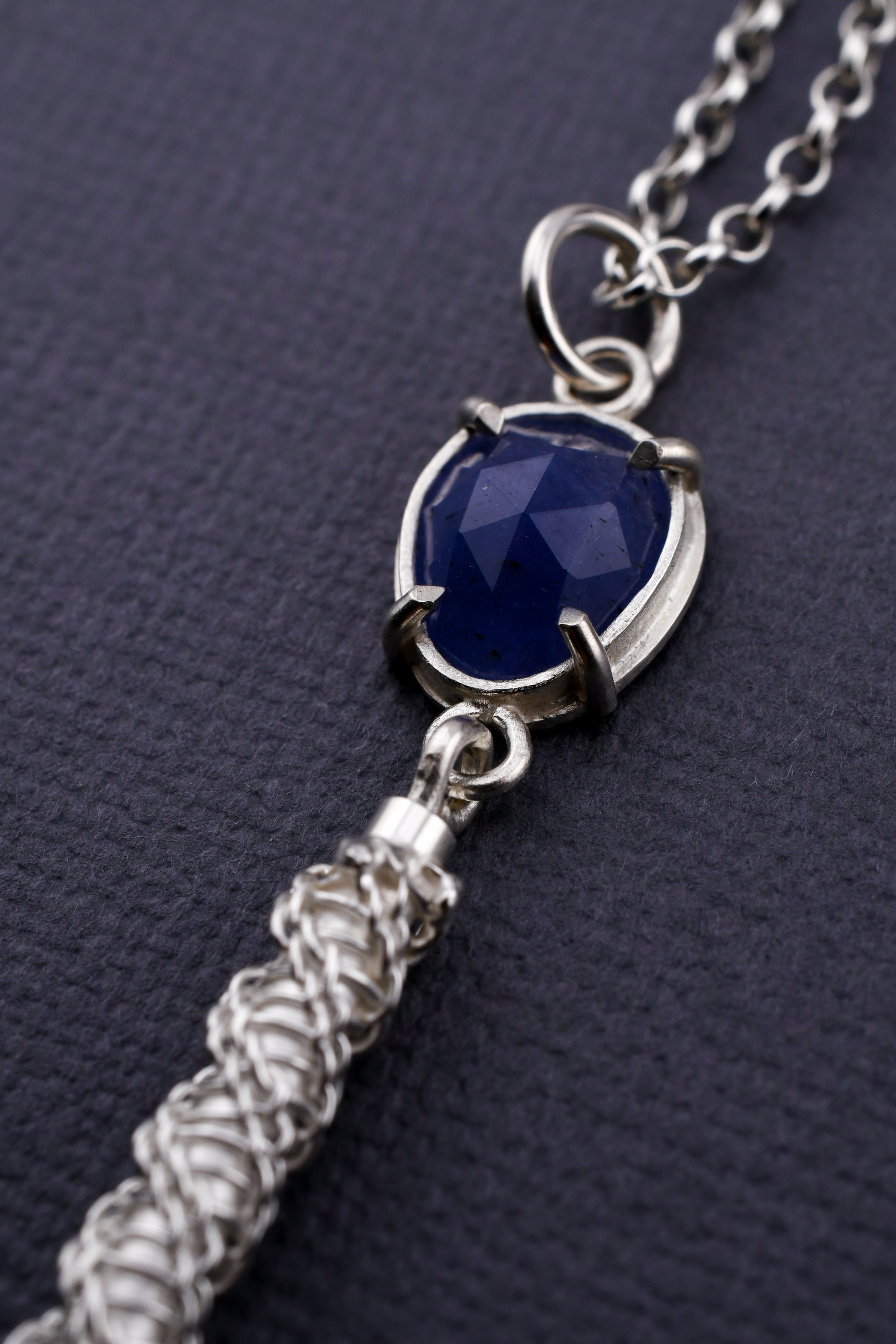 Necklace with blue pendant and silver chain on a dark background