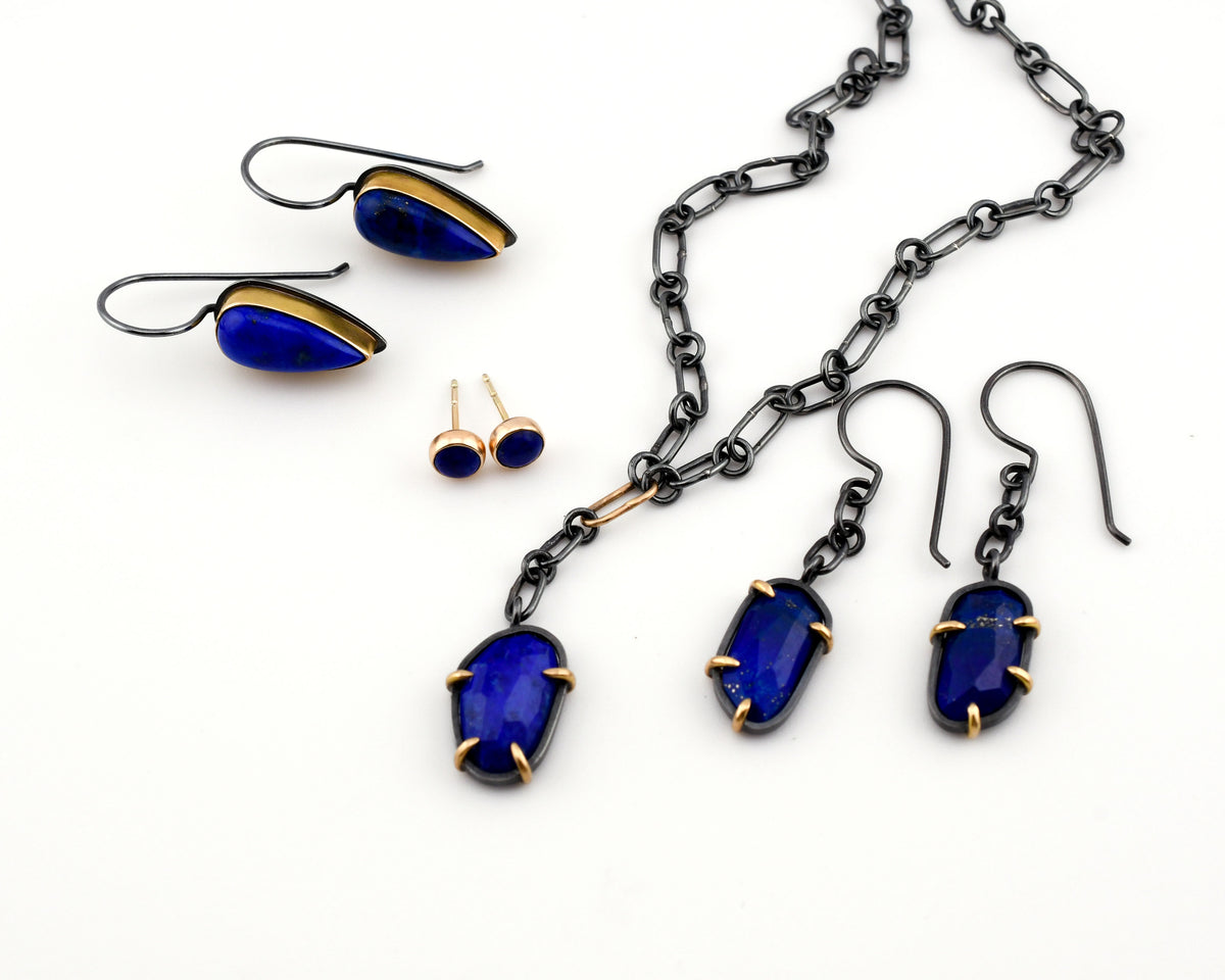 Deep blue lapis lazuli earrings, studs and necklace in blackened silver and 14k gold shown on a white background