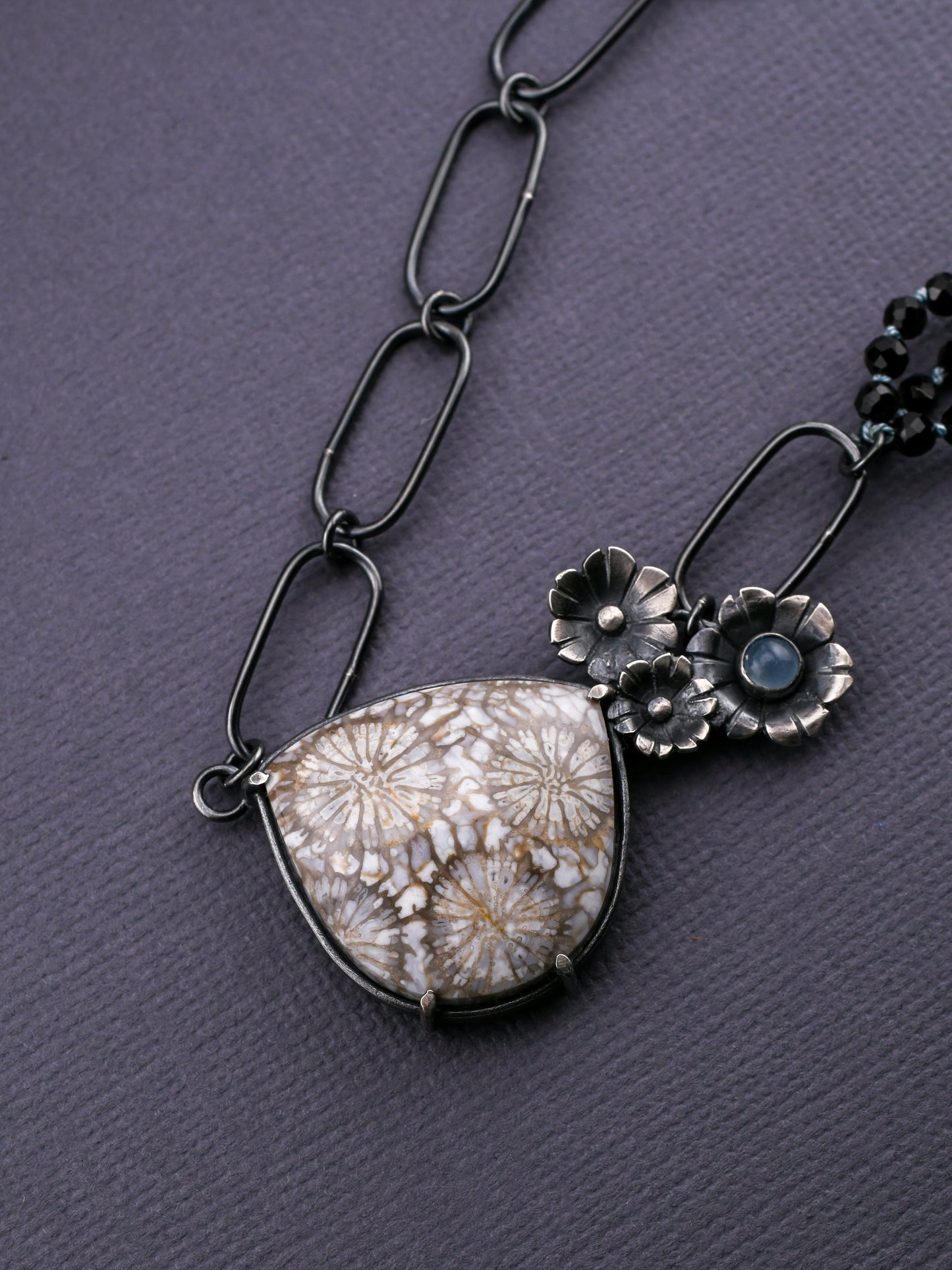 Necklace with floral pendants and a textured pendant on a gray background