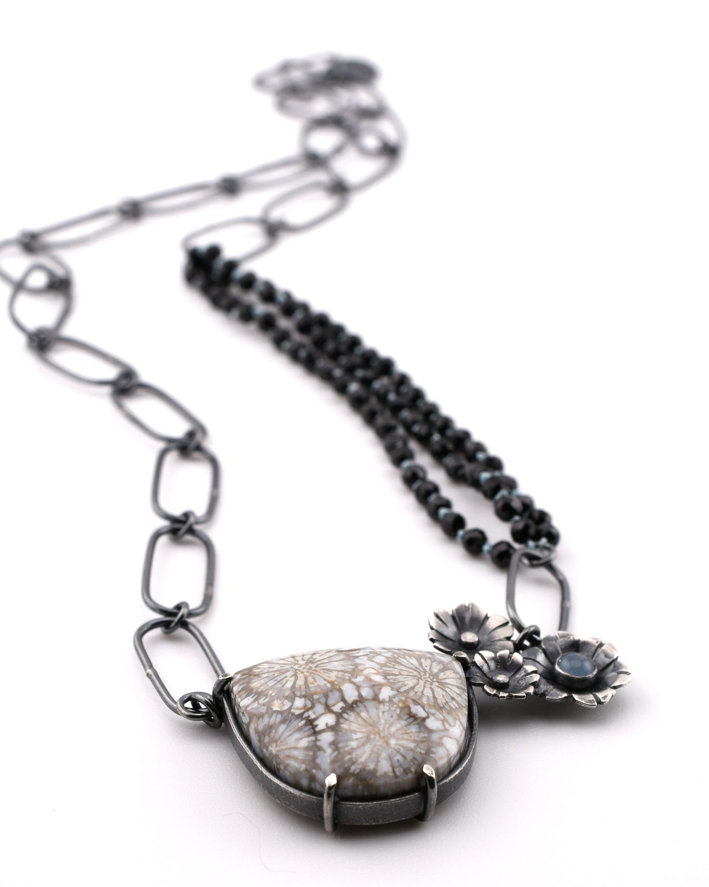 Necklace with a large stone pendant and floral elements on a white background