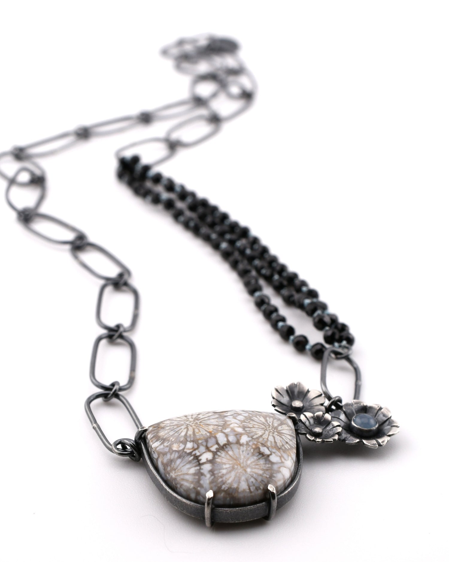 Necklace with a large stone pendant and floral elements on a white background