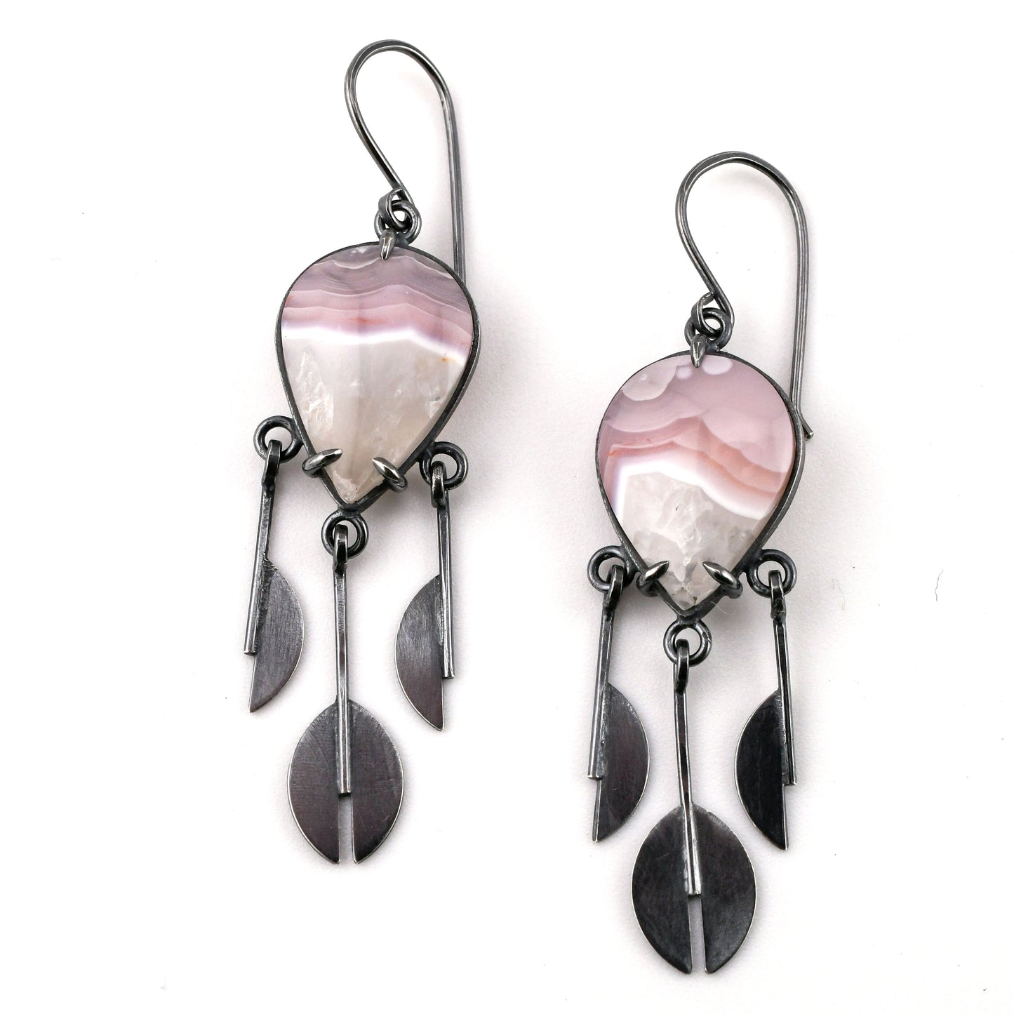 Pair of earrings with pink and white stone and silver leaf-like pendants on a white background