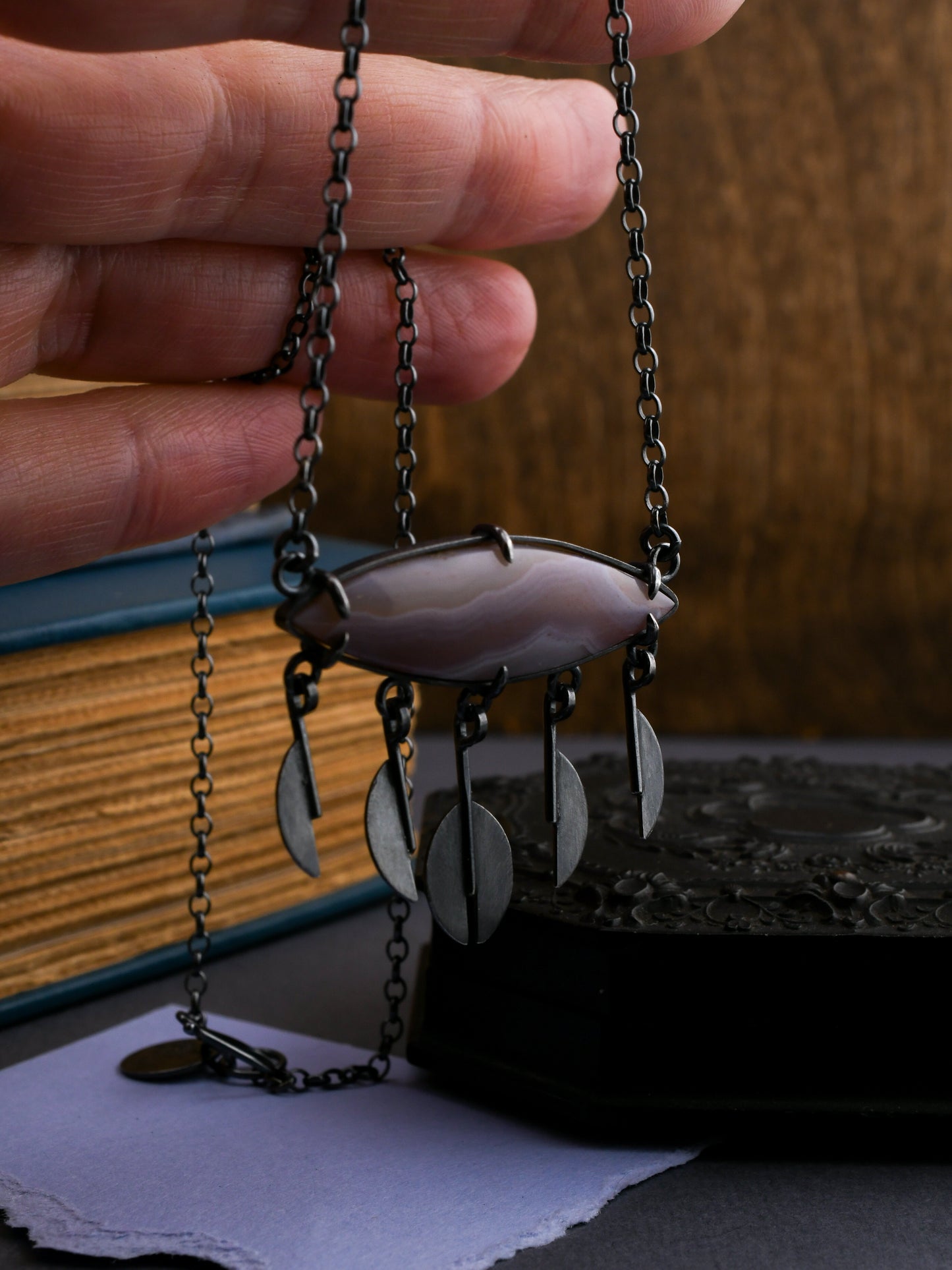Necklace with a pendant held by a hand, with a blurred background