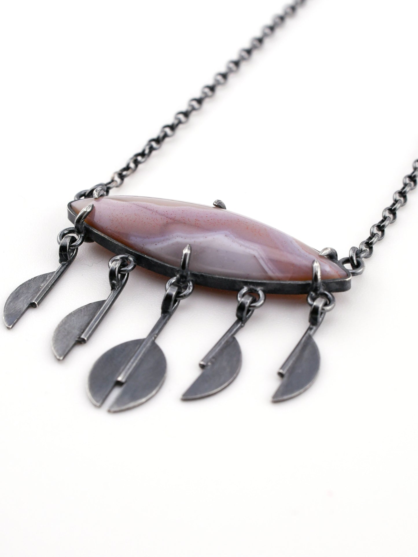 Necklace with a large lavender stone pendant and smaller silver raindrop pendants on a white background