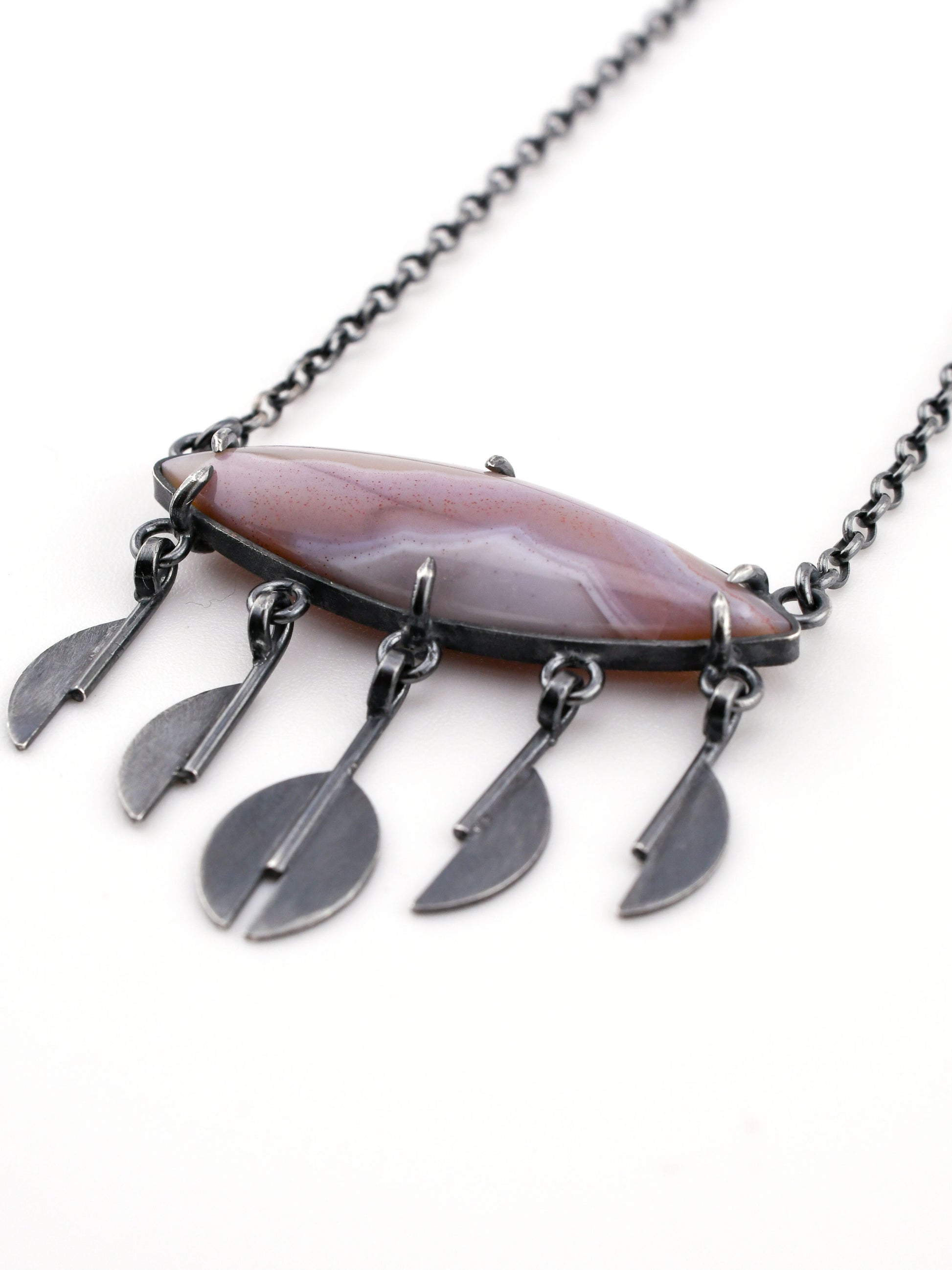 Necklace with a large lavender stone pendant and smaller silver raindrop pendants on a white background