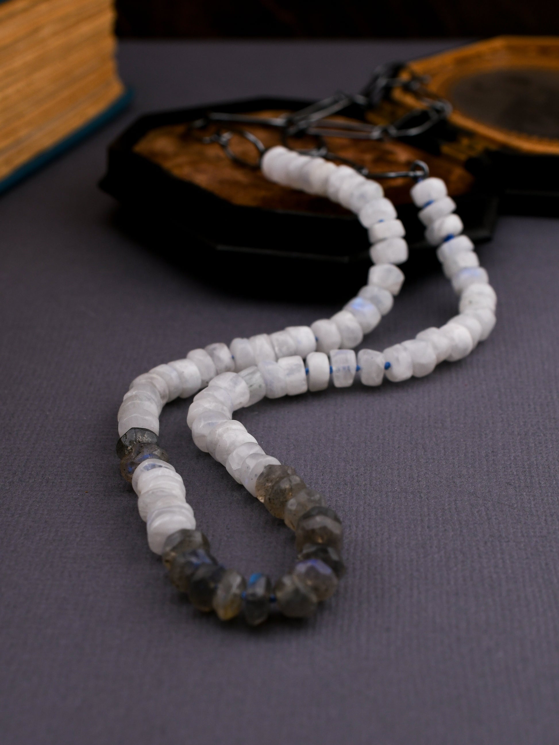 gray and white beaded necklace on a dark background