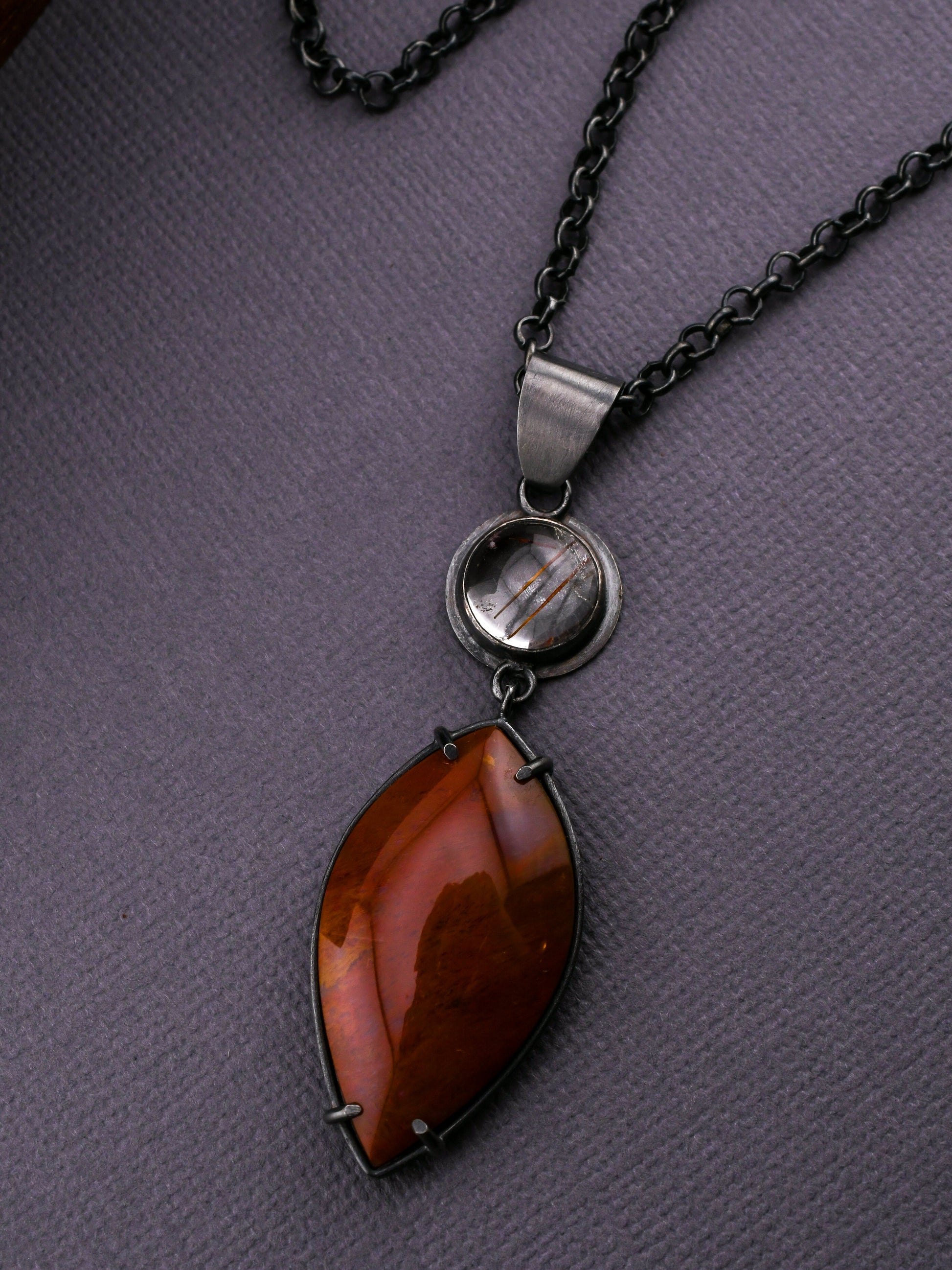 Necklace with a pendant featuring a red stone on a gray background