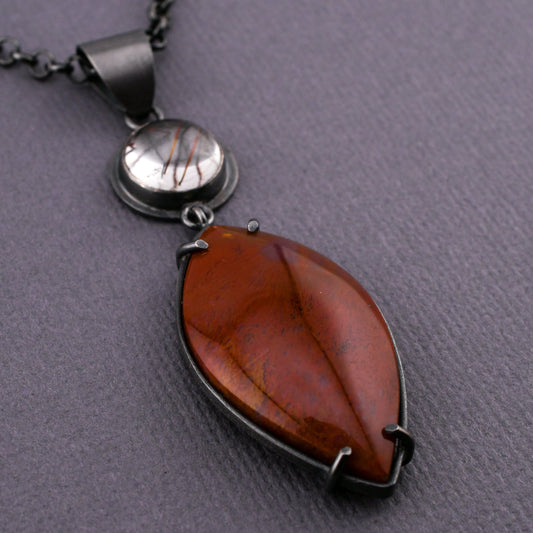 Necklace with a red stone pendant on a gray background