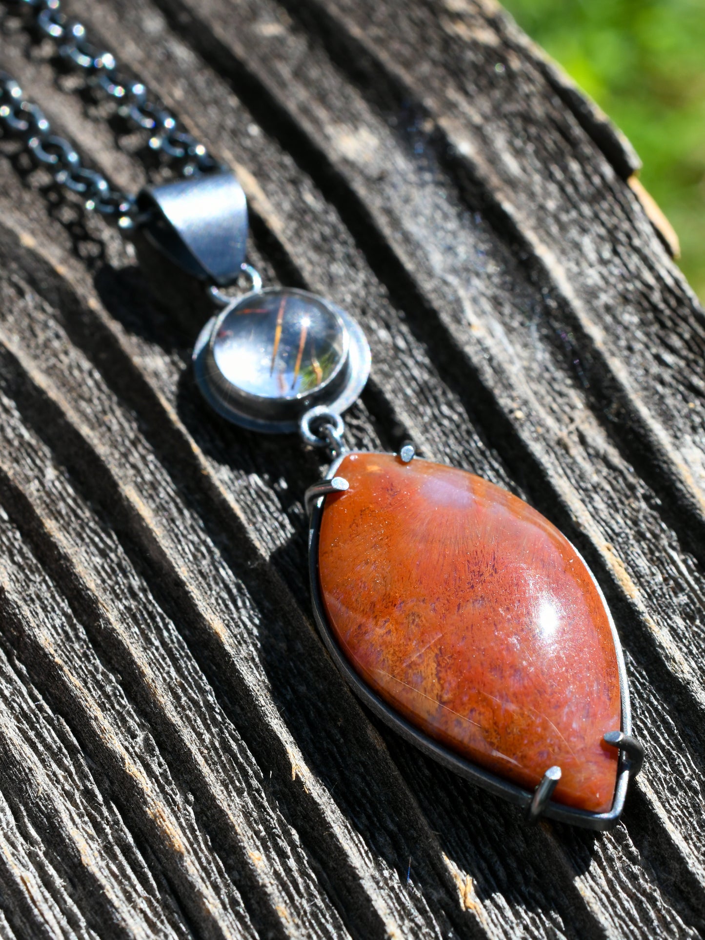 Necklace with a red stone pendant on a wooden surface
