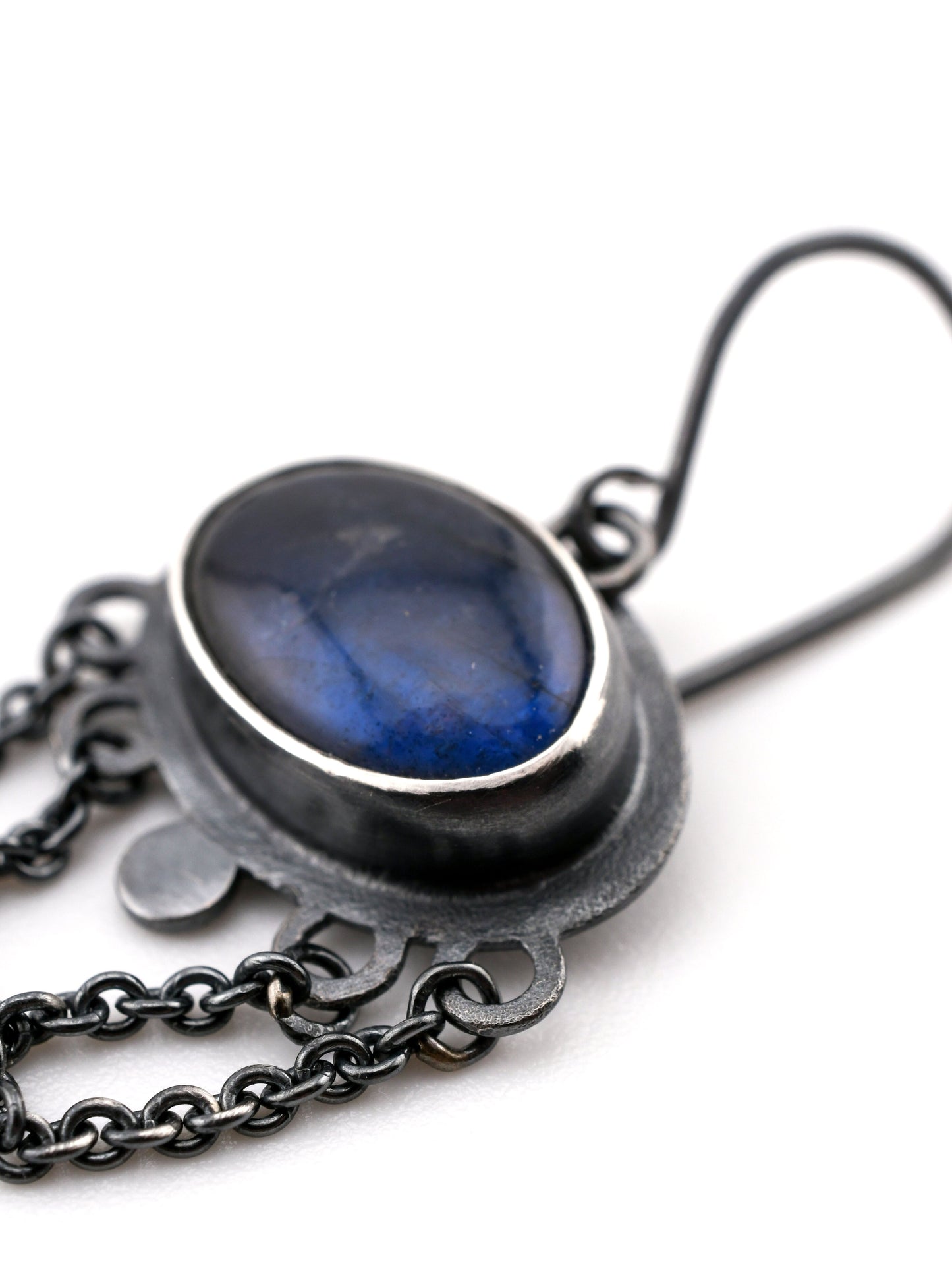 Jewelry with a blue stone and black metal chain on a white background