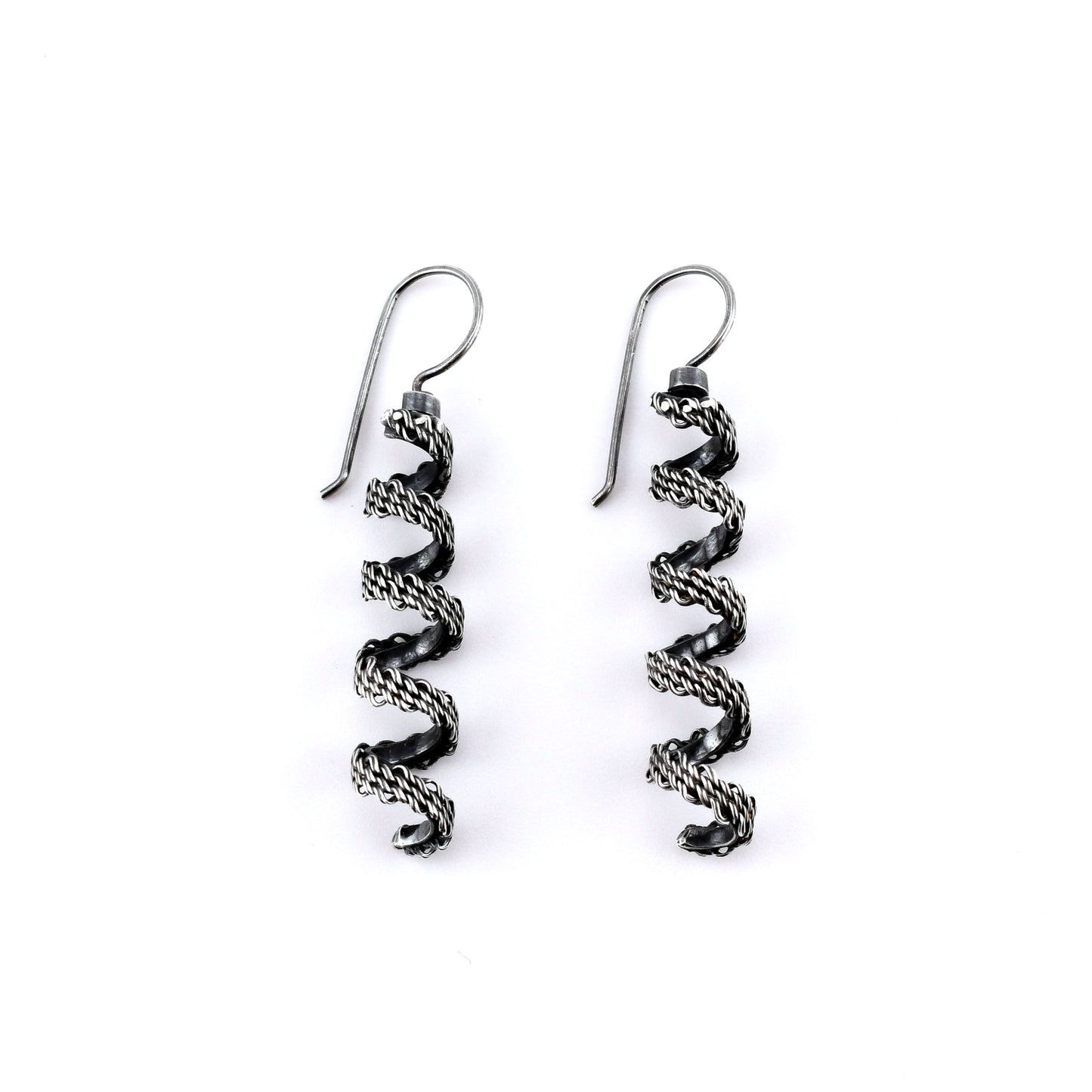 Pair of  woven silver spiral earrings on a white background