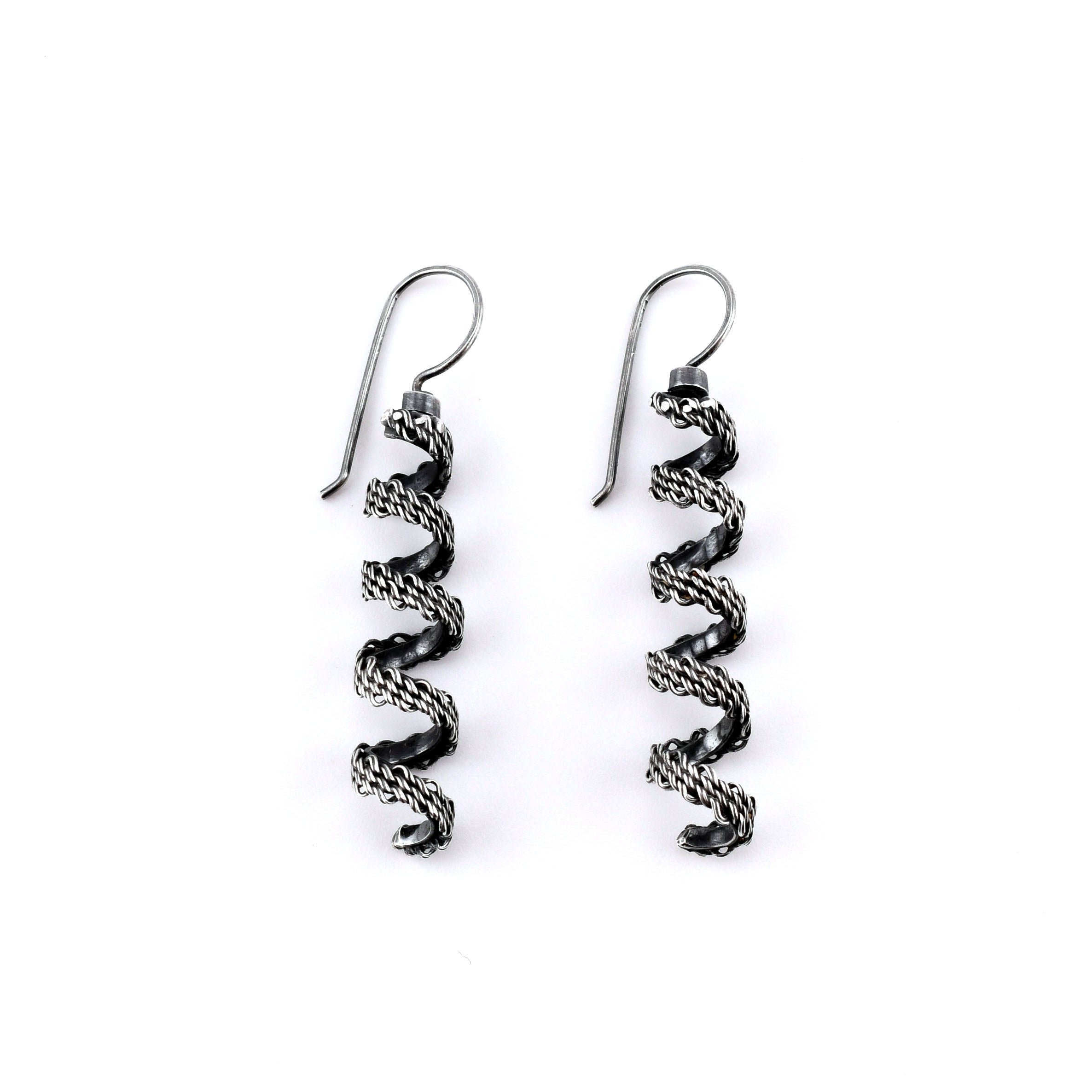 Pair of  woven silver spiral earrings on a white background